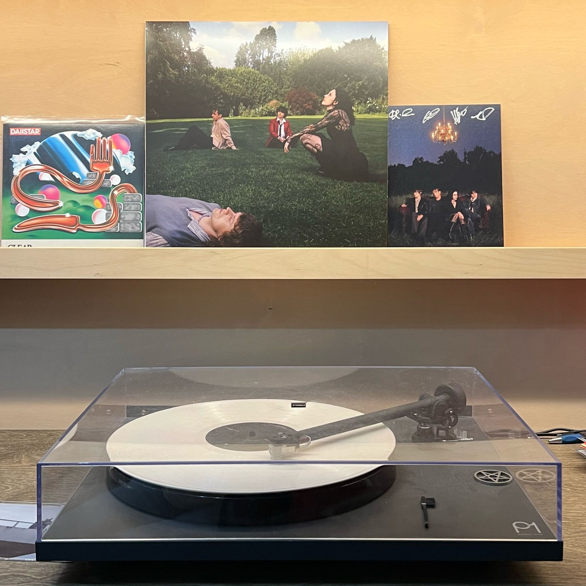 White (or maybe cream?) vinyl playing on turntable with alternate cover art in the background