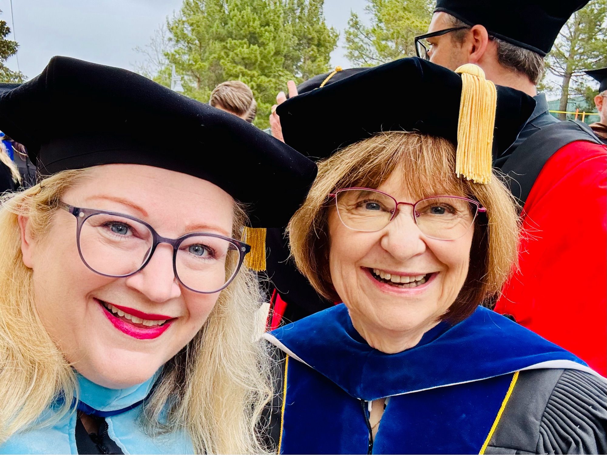 Two professors wearing regalia prepare to celebrate graduation