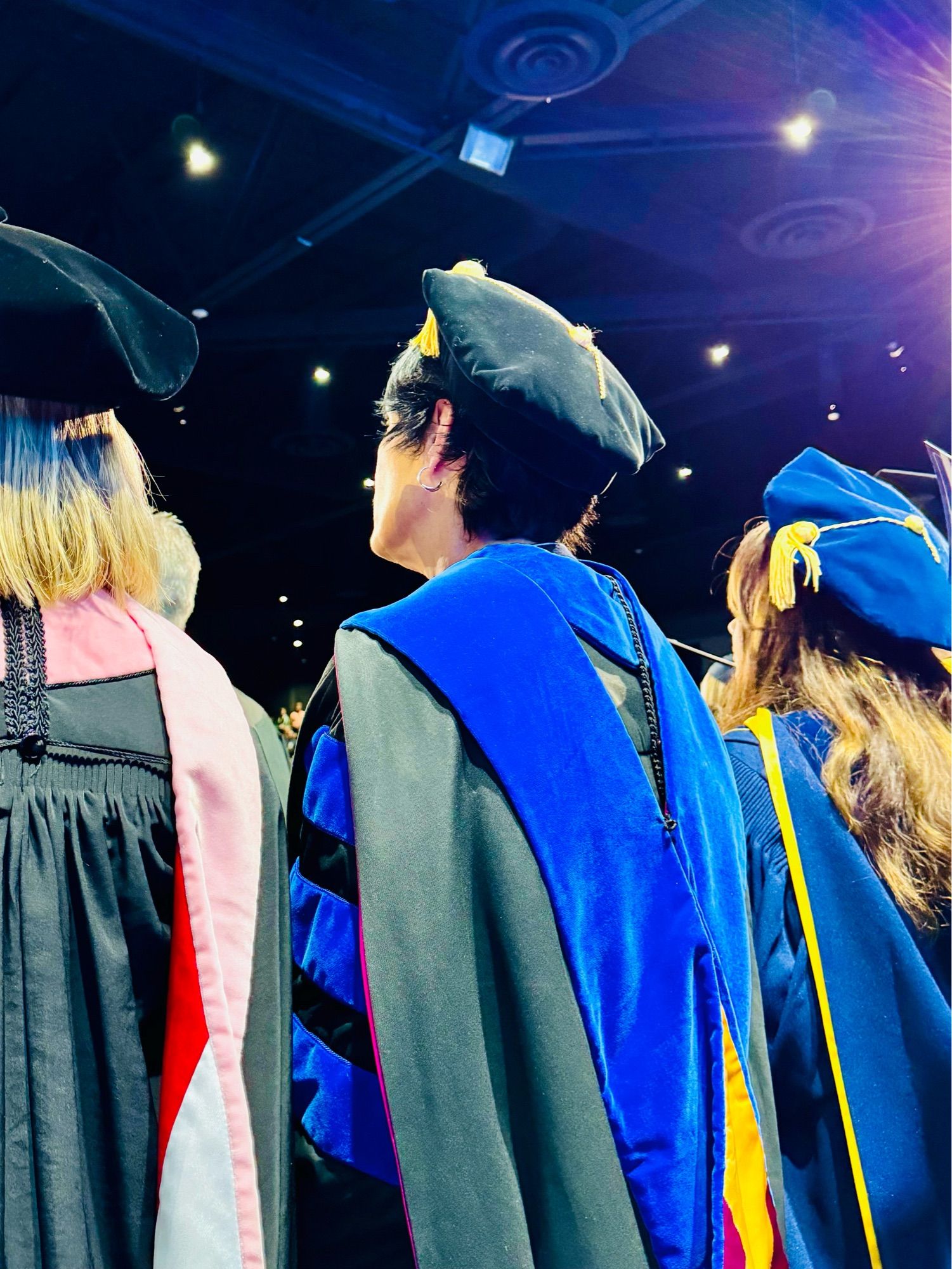 Back of three professors wearing regalia during a graduation ceremony