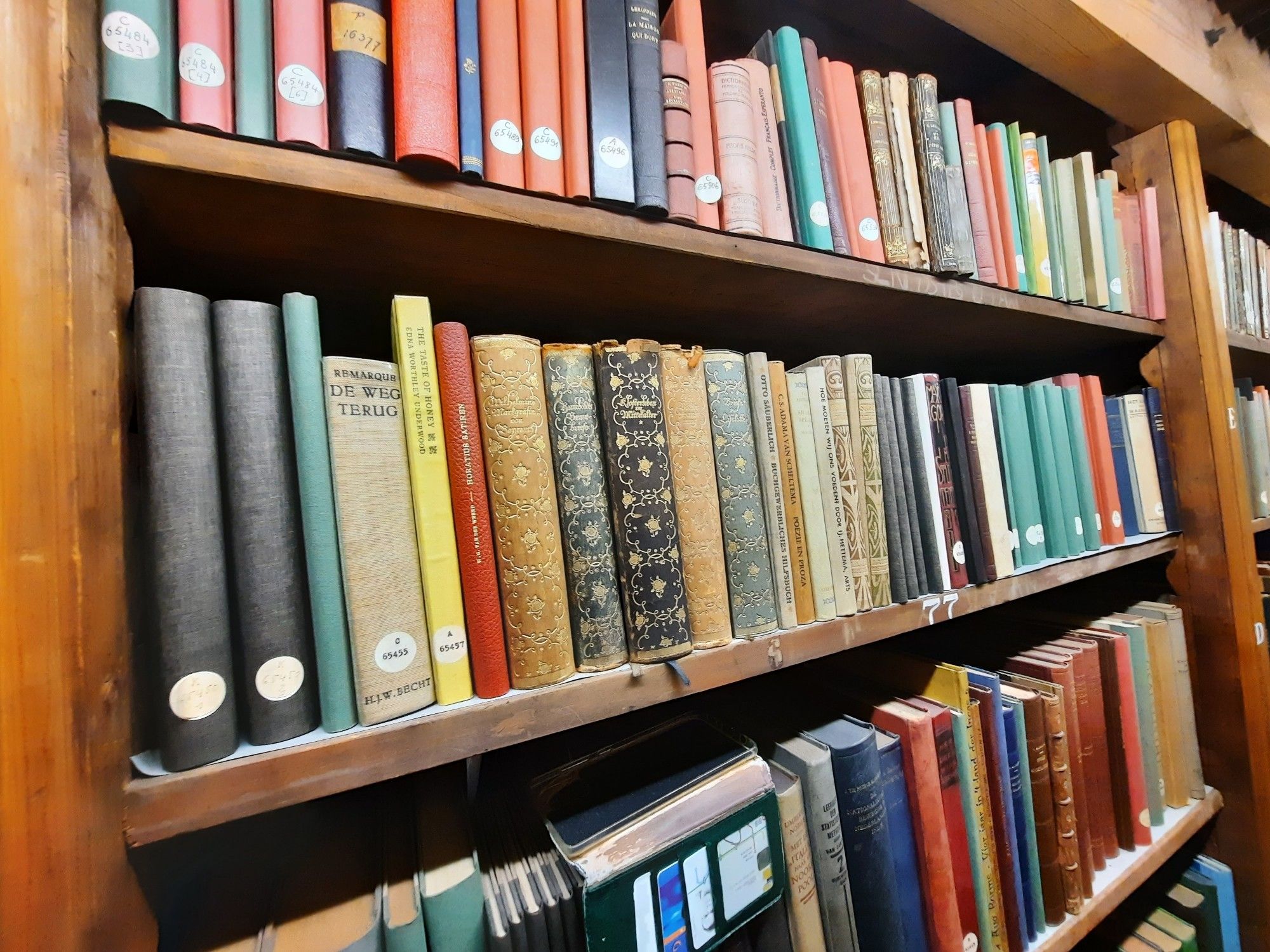 A row of colourful book spines in a wooden cabinet.