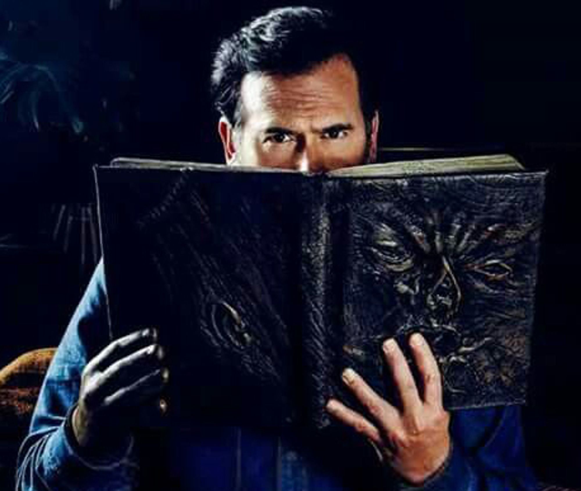 Bruce Campbell as Ash in Evil Dead, reading the Necronomicon. He is peering over the top of the open book with a slight scowl. The book is obviously made of human flesh, with a face flattened on the cover.