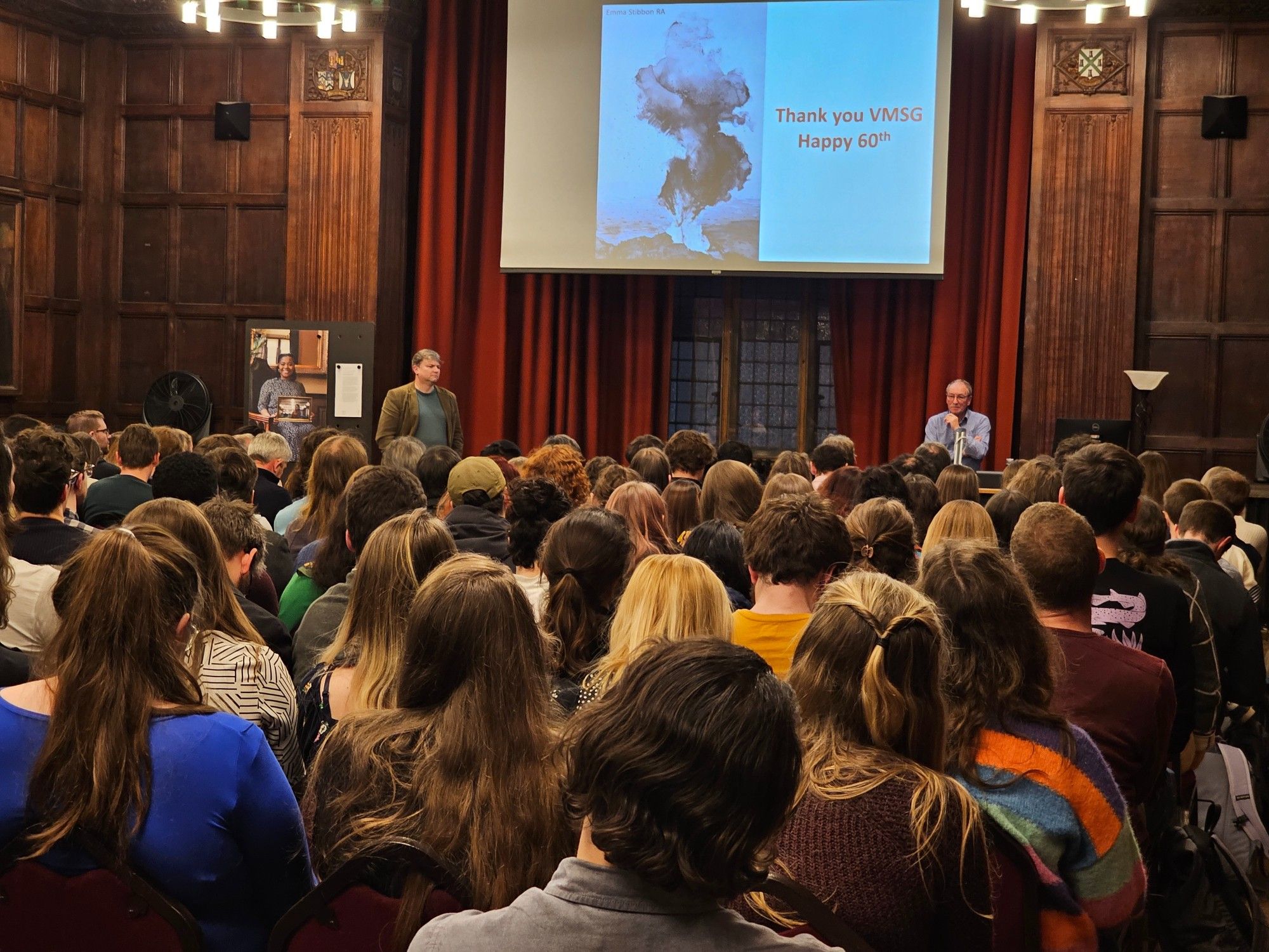 Photo of Sir Steve Sparks giving a 60th anniversary talk looking back on 60 years of VMSG to a packed hall of attendees