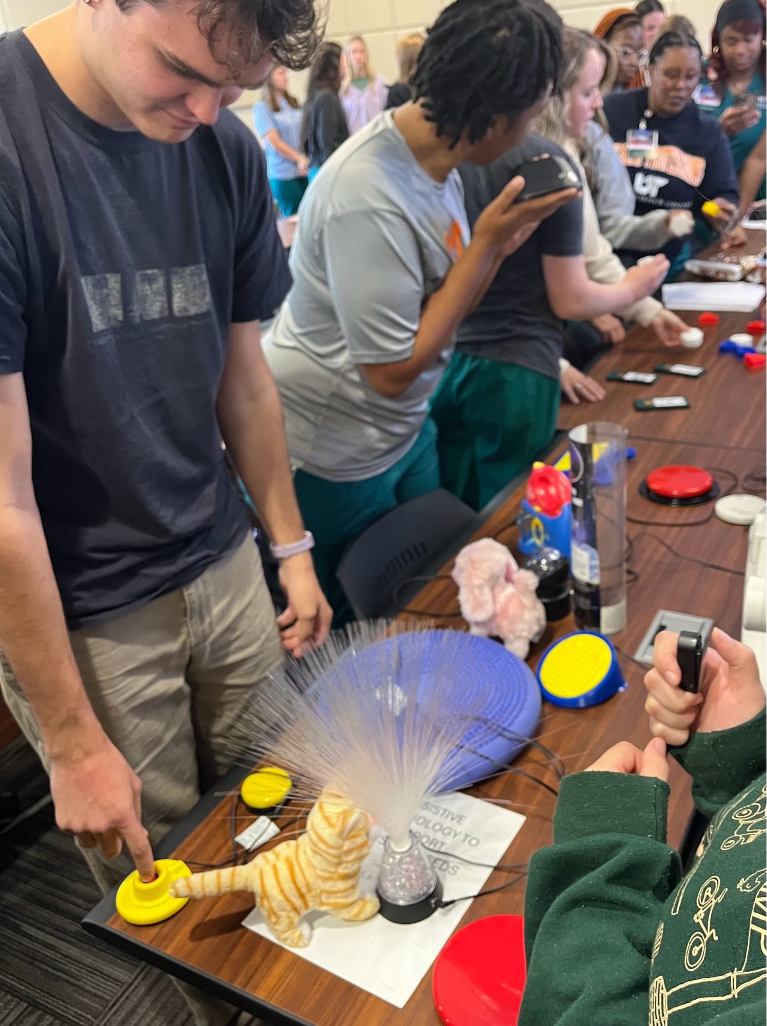 Many graduate students interacting with switch activated toys, single message switches, and 3D printed symbols