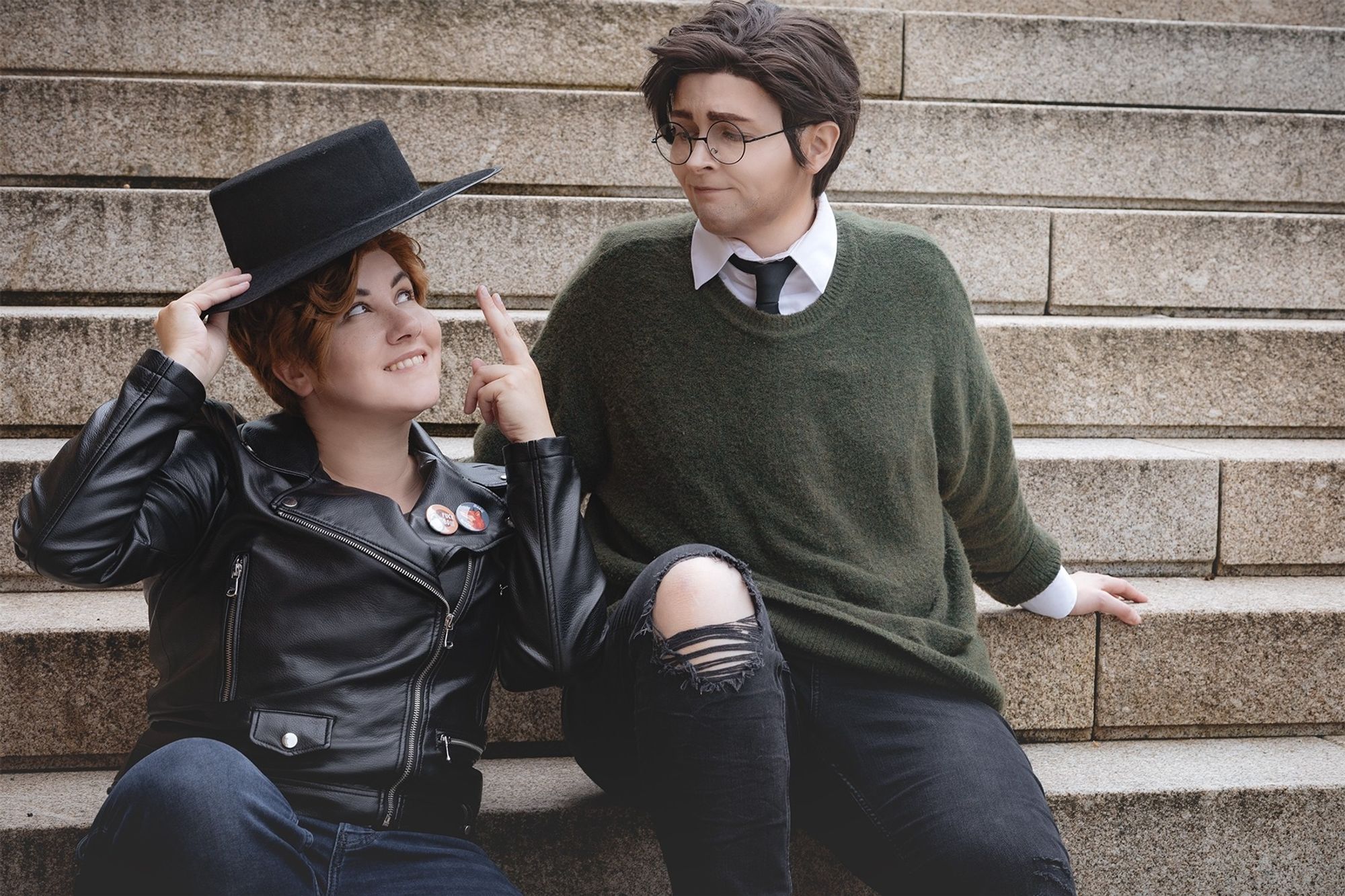 Gregg and Angus cosplayers sitting on stairs and Gregg stealing Angus hat