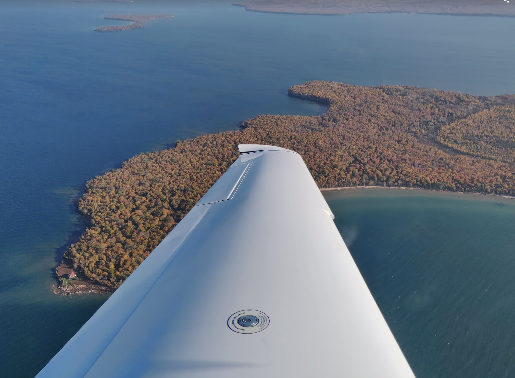 photo across a white plane wing looking at an island with fall foliage