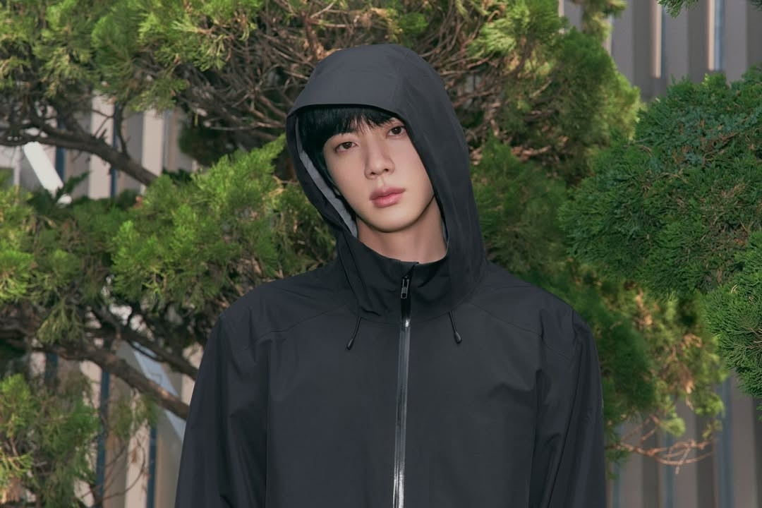 Close-up photo of Jin wearing the same clothes and in the same place as the previous photo.