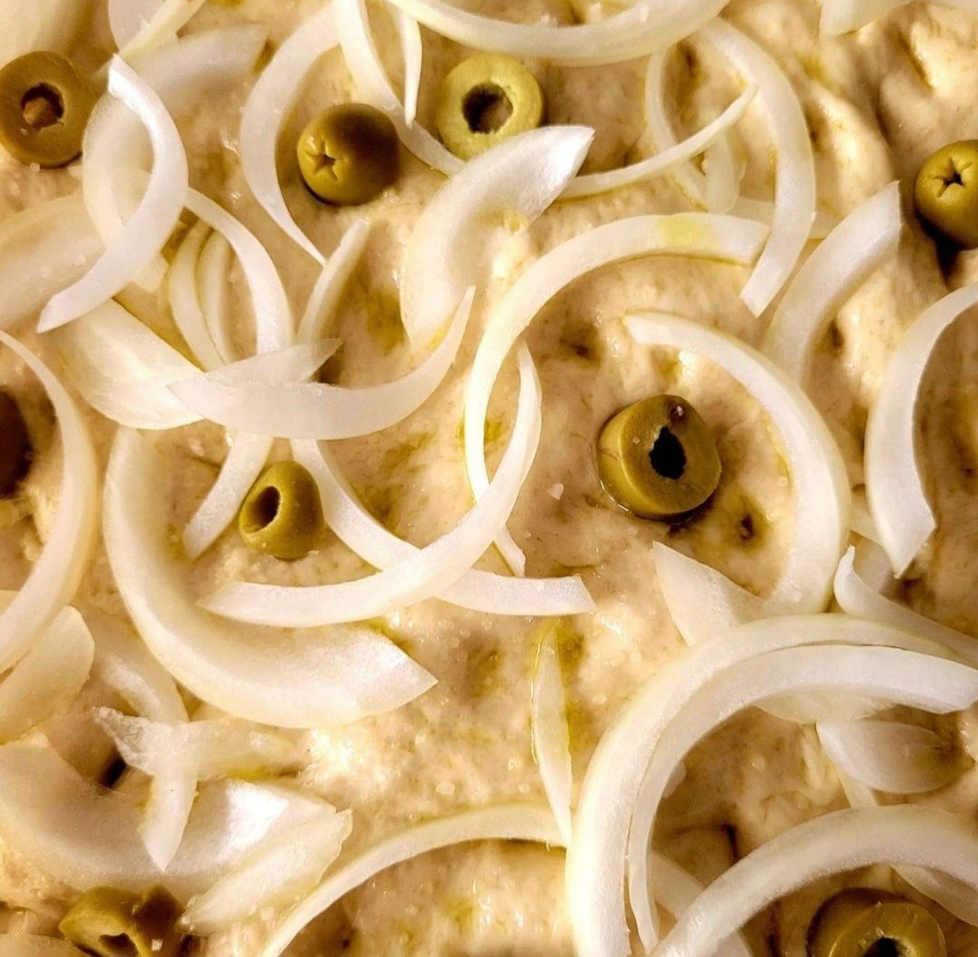 Ready for the oven focaccia. With green olives and white onion