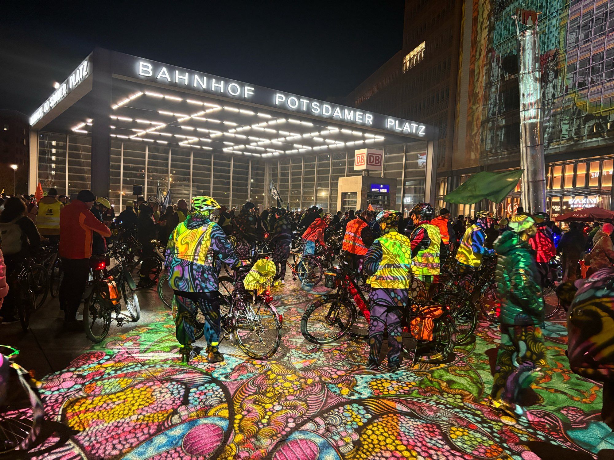 Auf dem Potsdamer Platz werden wartende Fahrradfahrer von Festival of Lights Lichtern angestrahlt