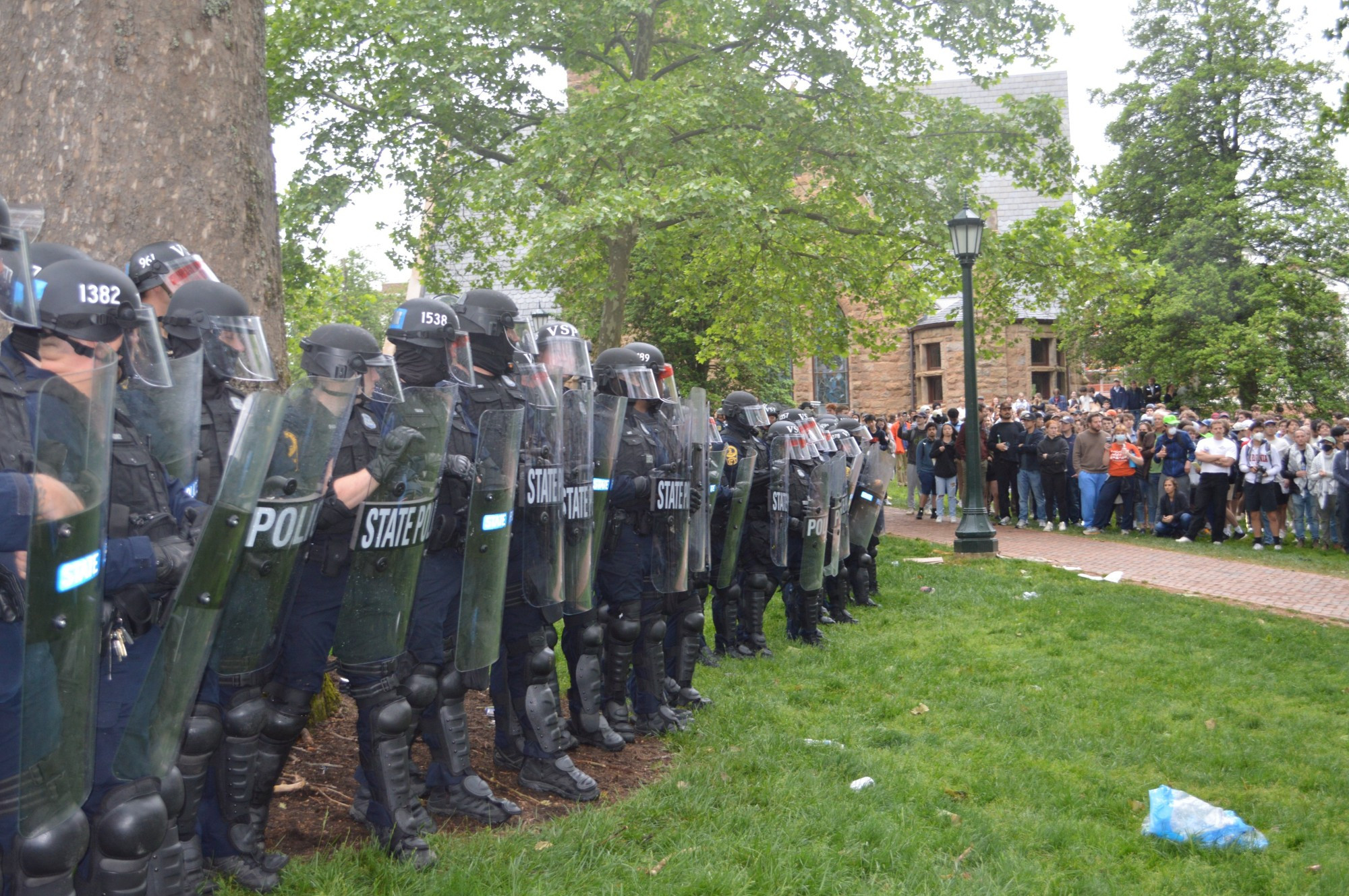 Police in riot gear hold riot shields in formation between the Rotunda and Chapel at the University of Virginia as they prepare to push anti-genocide protesters into the street after University President Jim Ryan authorized the Virginia State Police to beat and arrest UVa students, faculty, and staff who were protesting Israel's ongoing genocide of Palestine in an encampment on the Grounds of the University of Virginia.
