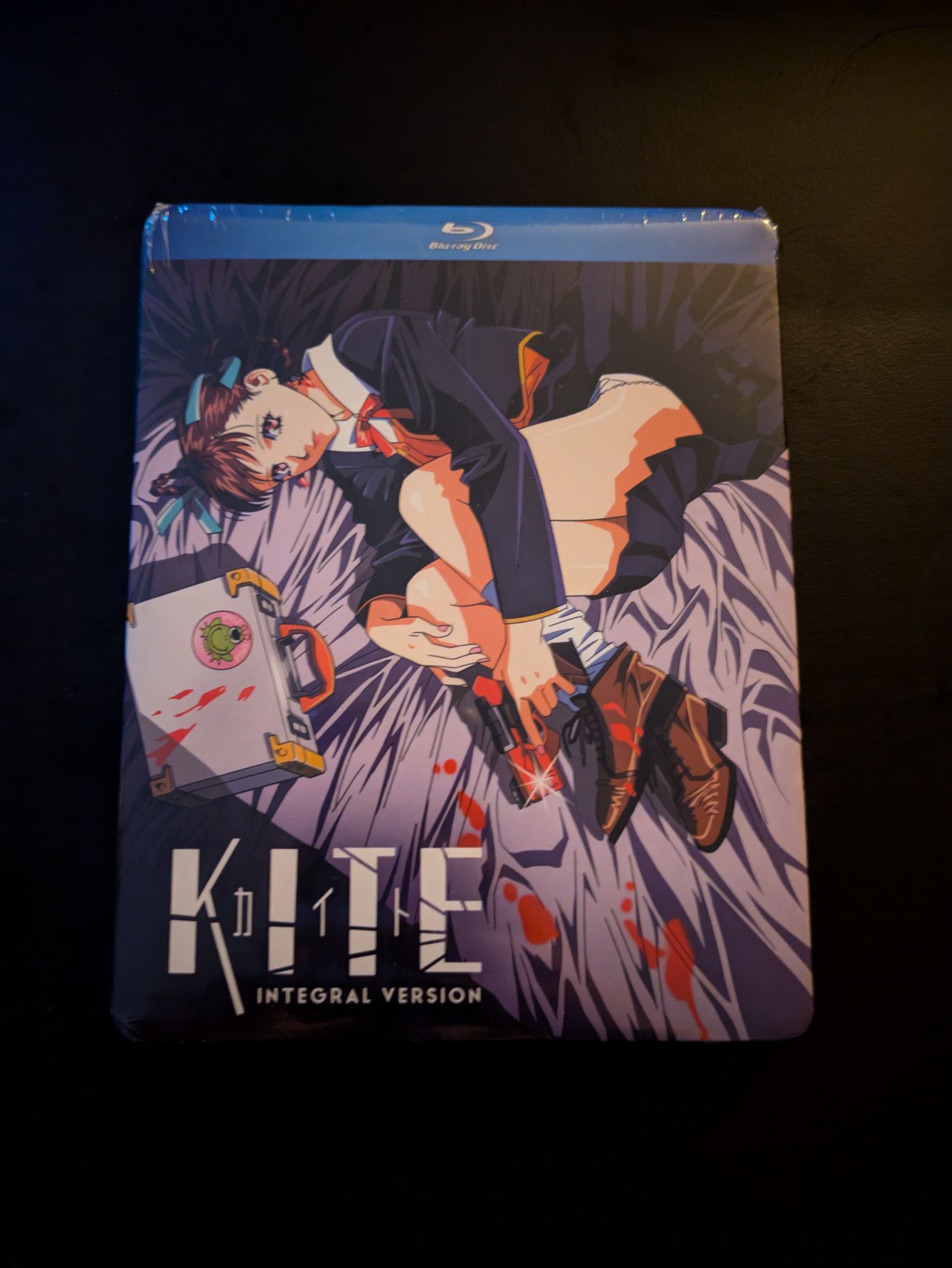 Front cover of Kite (integral version) Blu-ray featuring the main character Sawa laid out on the bed with her gun and blood on the sheets.