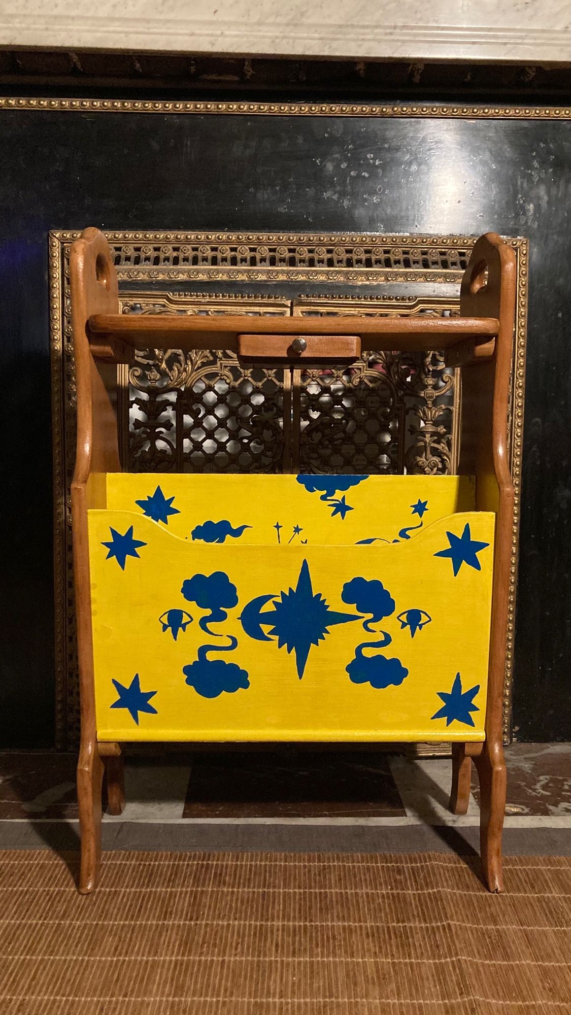 Porte revue en bois, le centre est peint en jaune et bleu avec des motifs nuages, étoiles, soleil, lune, œil, les côtés sont dans le bois original couleur chêne.