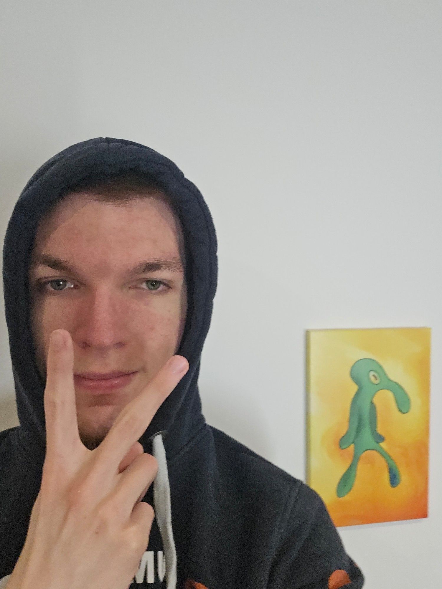 Maingron wearing a hoodie in front of a SpongeBob-Series painting