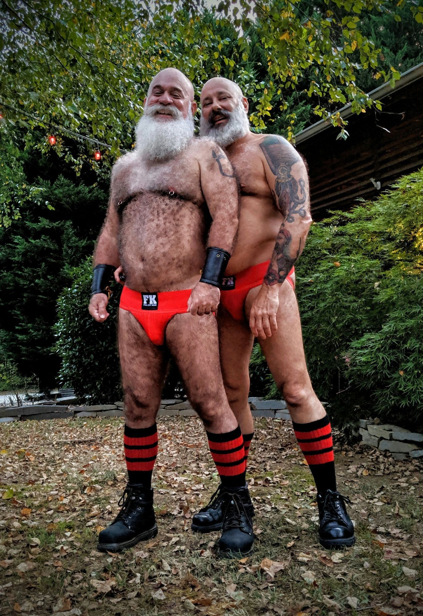 Two hairy bear men wearing red jockstraps and boots