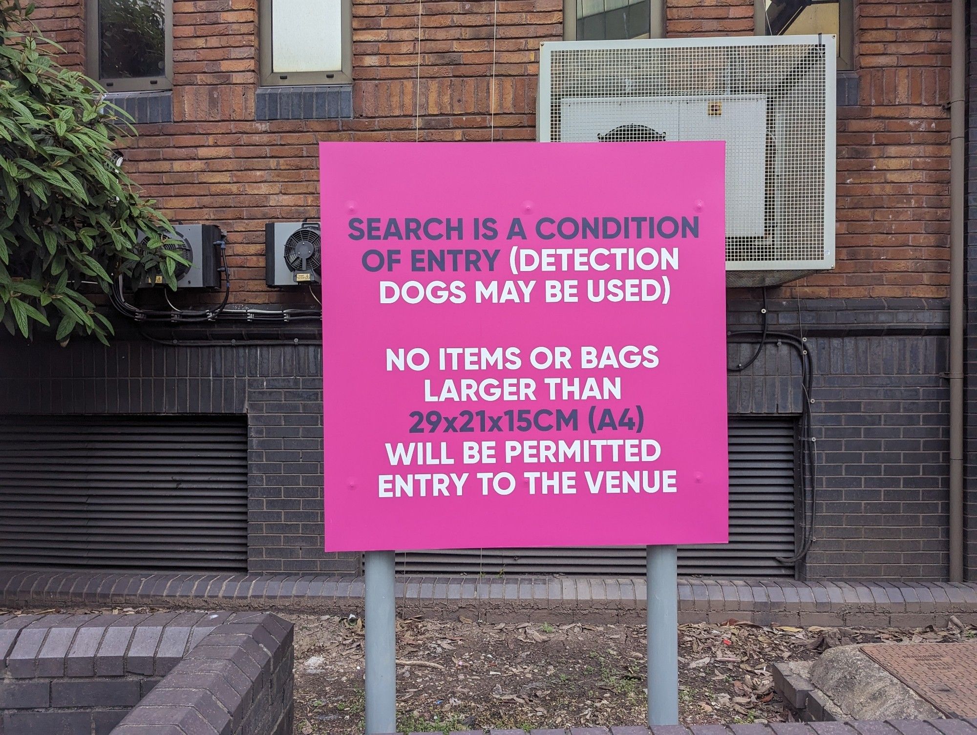 A sign with the following text:

Search is a condition 
Of entry (detection
Dogs may be used)
No items or bags
Larger than
29x21x15cm (A4)
Will be permitted
Entry to the venue