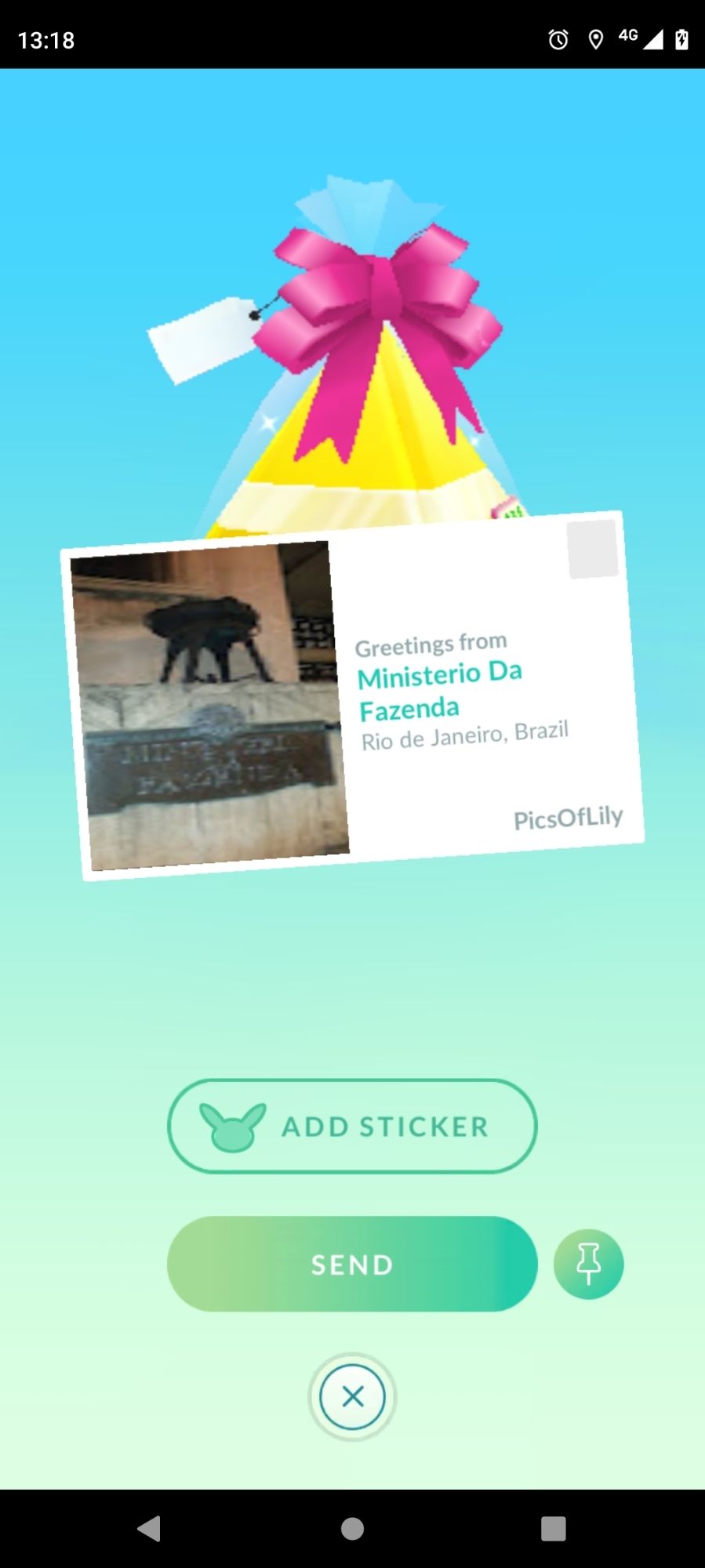 Captura de tela do jogo Pokémon Go com da tela de envio de presentes. Na imagem há um presente com cartão postal do "Ministério da Fazenda". A mensagem do cartão diz "Greetings from Ministério da Fazenda, Rio de Janeiro, Brazil".