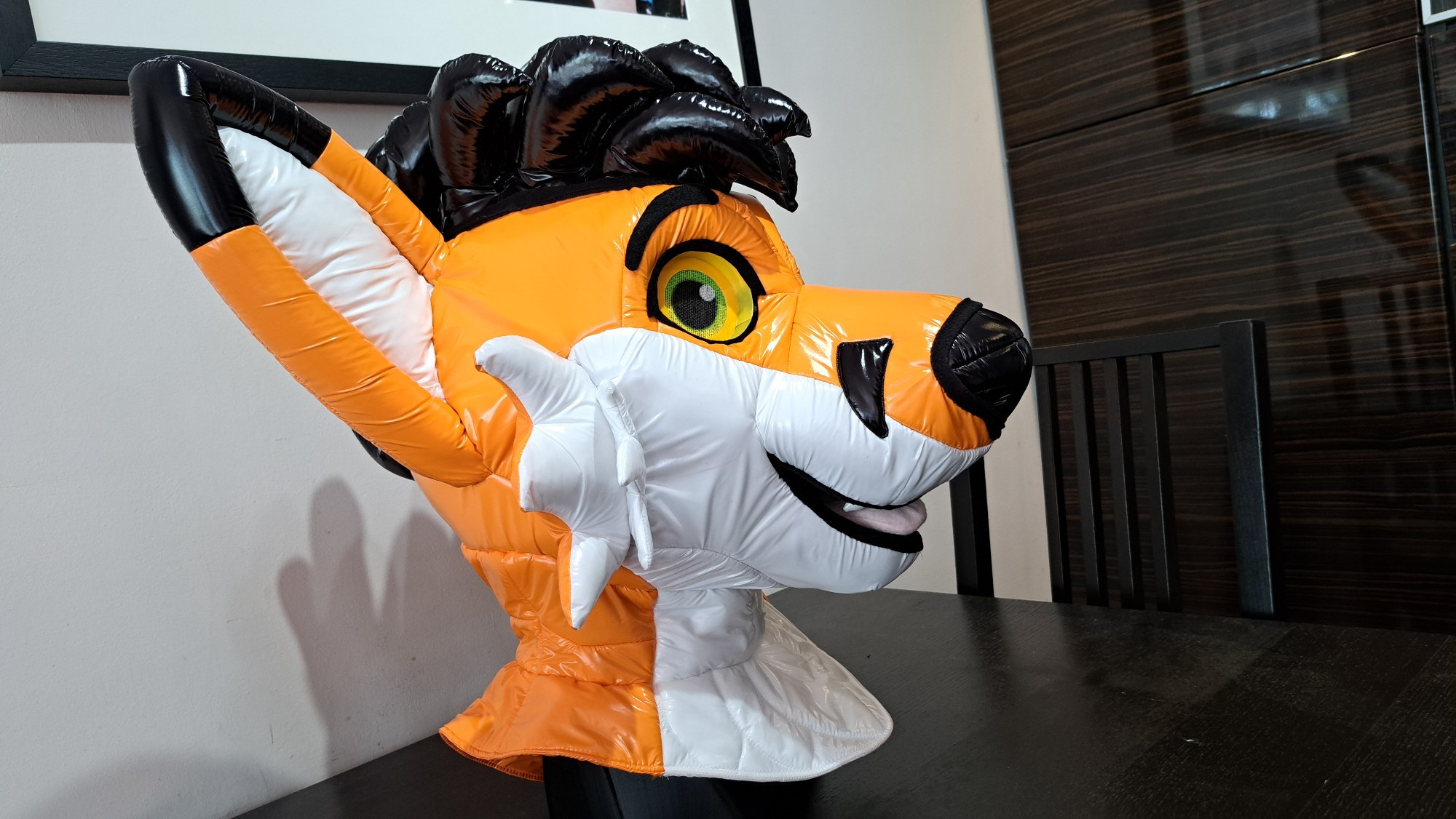 Flynn, the orange nylon fox. Made of shiny orange and white nylon on a foam headbase, with shiny black spiky hair.