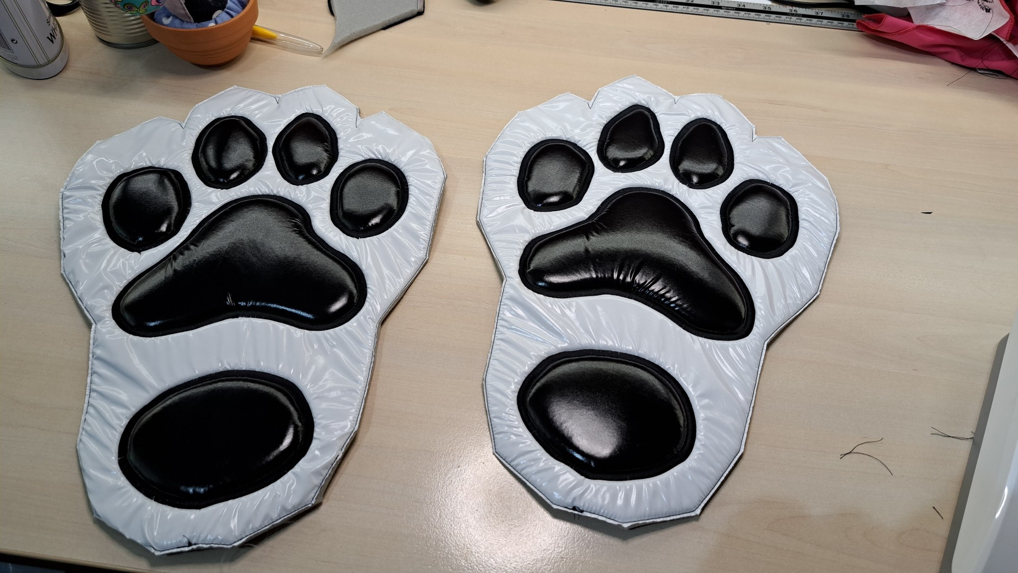 The base of a pair of feetpaws made of shiny white nylon with black pawpads, appliquéd with a black satin stitch