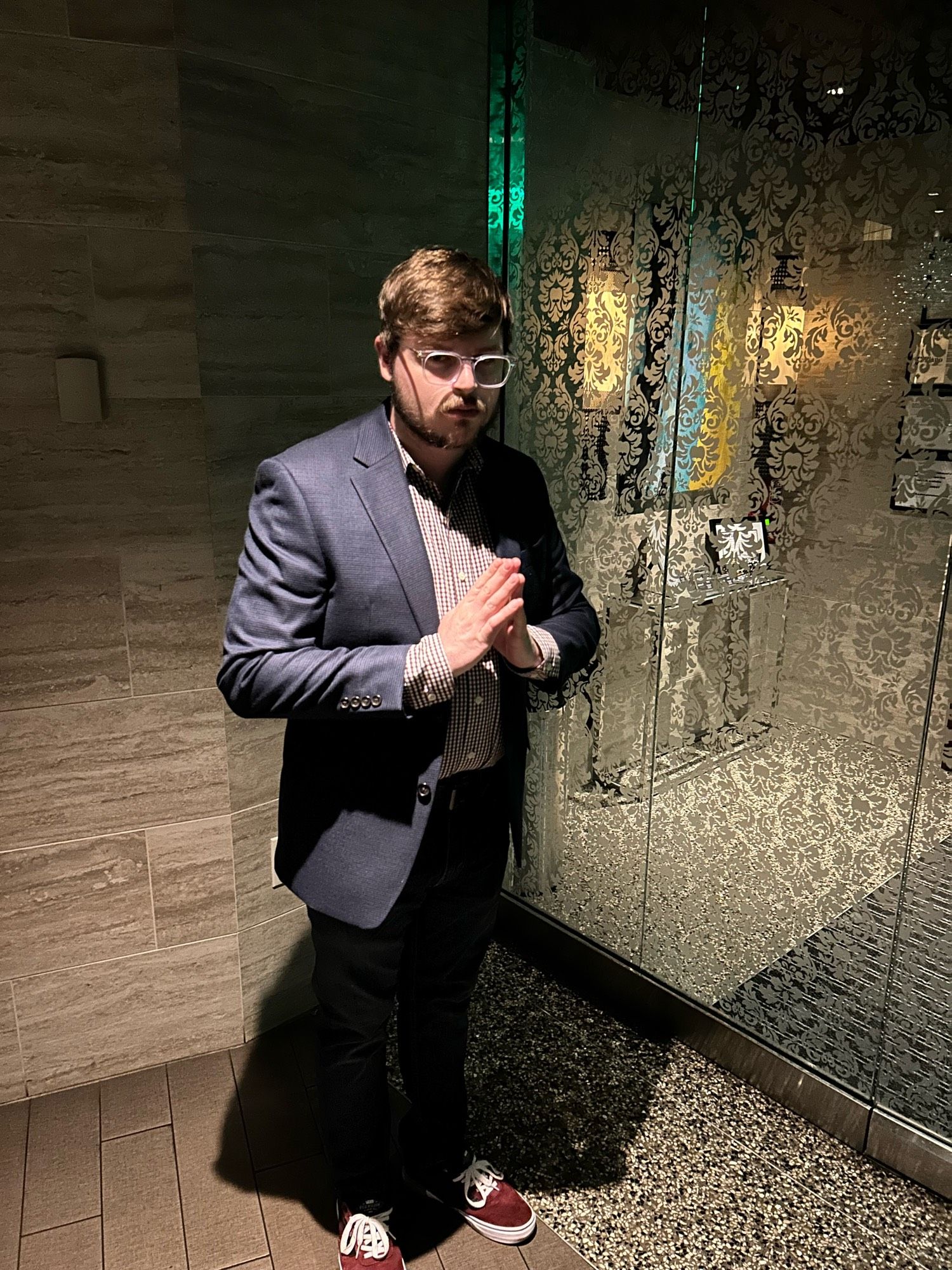 Evil man out at a fancy dinner. He is very short (5’7”) and very evil (the freakin’ worst). This man has glasses, is standing in front of a glass door, and red vans. Man is E V I L. He is also 27 years old now.