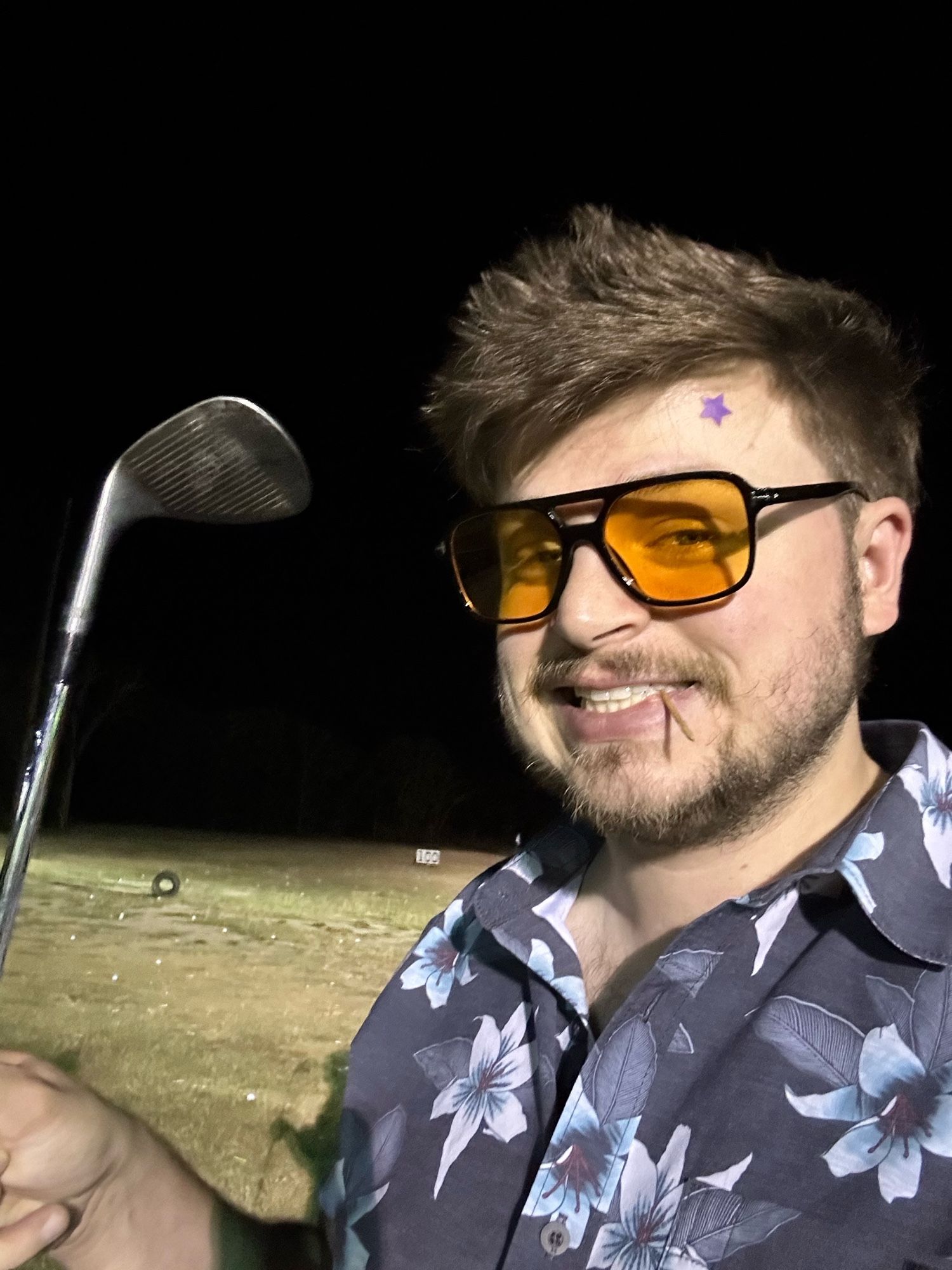 Selfie of a silly hockey man holding a golf club. He has his cool orange sunglasses and Hawaiian shirt and he has a toothpick in his mouth and a star patch on his forehead.