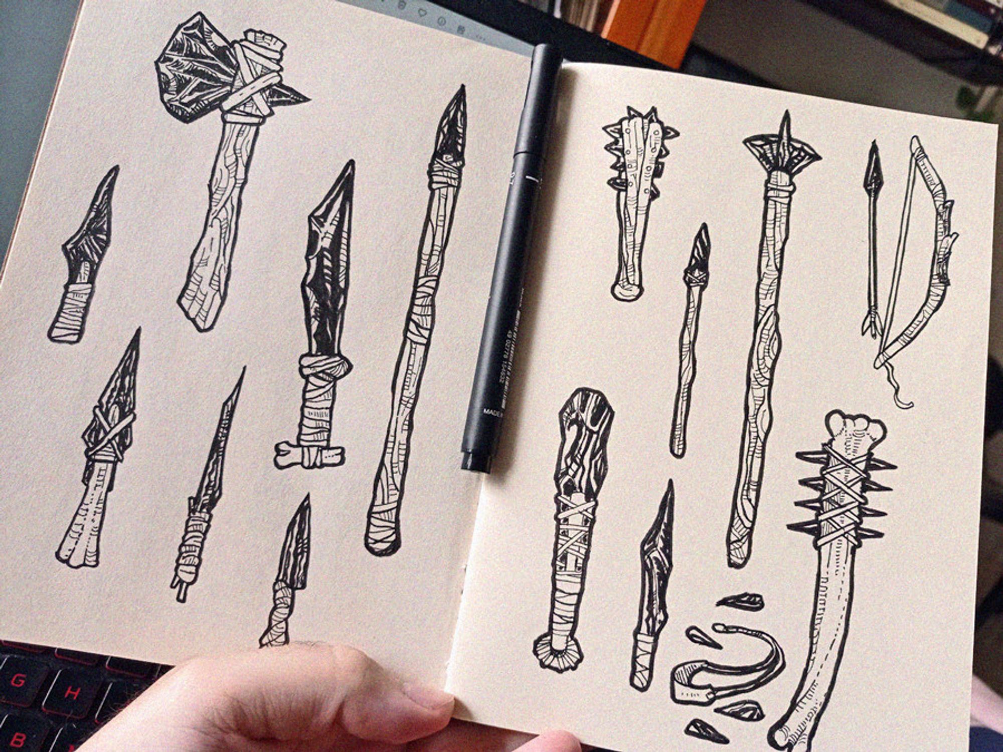 sketchbook page photo with the drawings of several stone age obsidian weapons as daggers, spears and clubs.