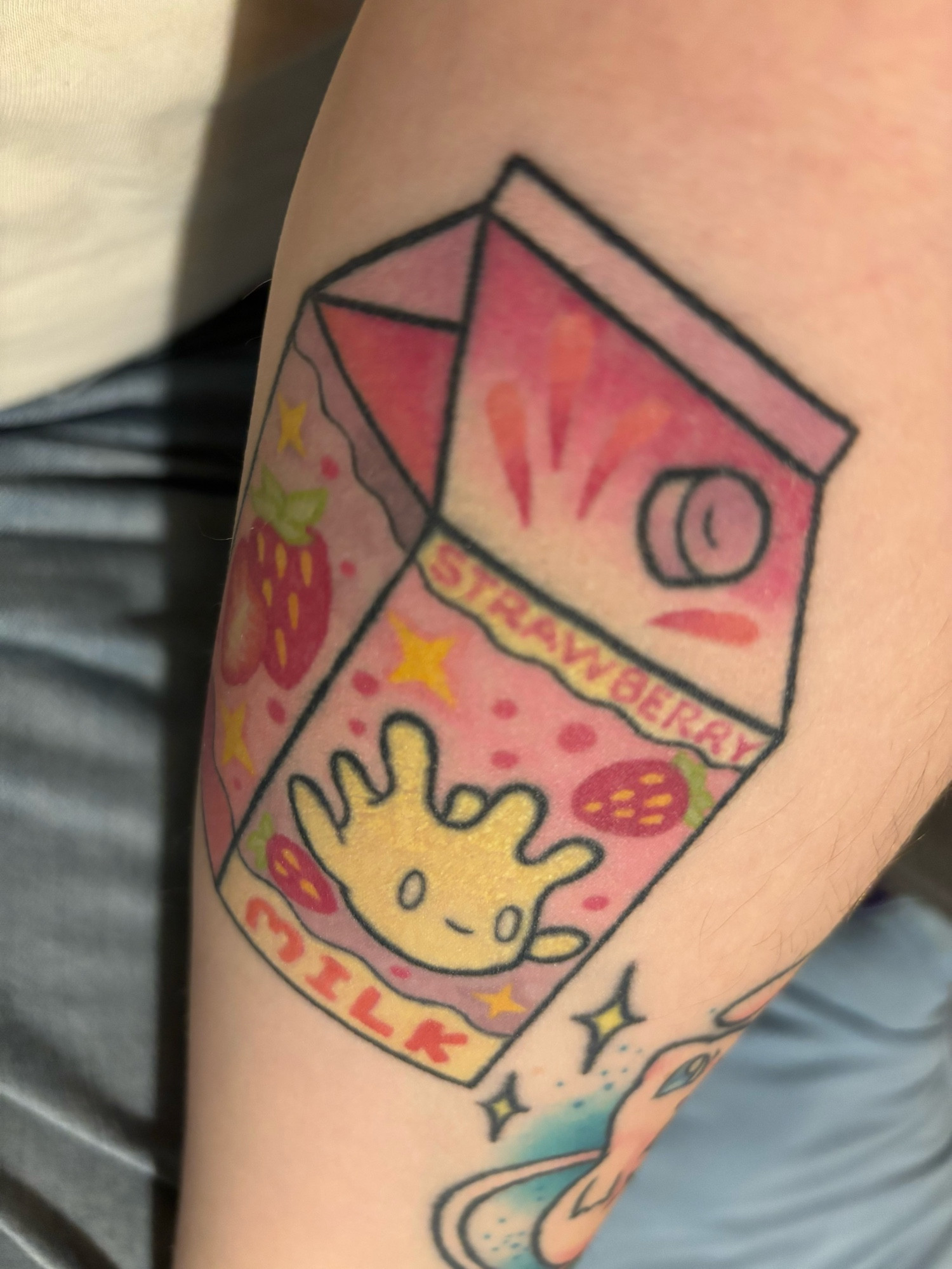 A tattoo of a strawberry milk carton but it’s the Pokémon Milcery