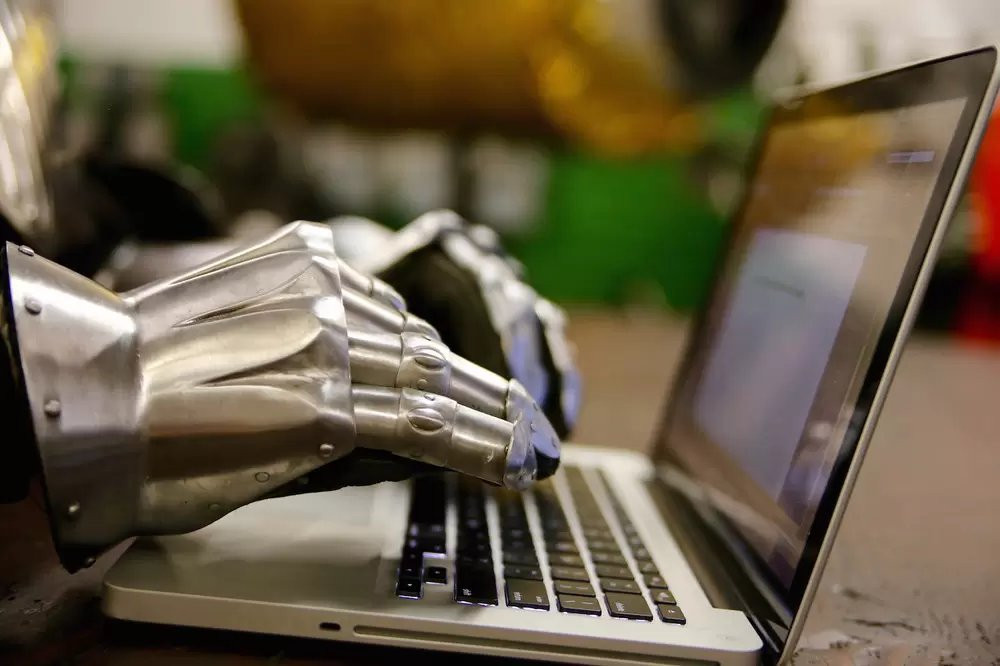 a photo showing a macbook with gauntleted hands typing on it