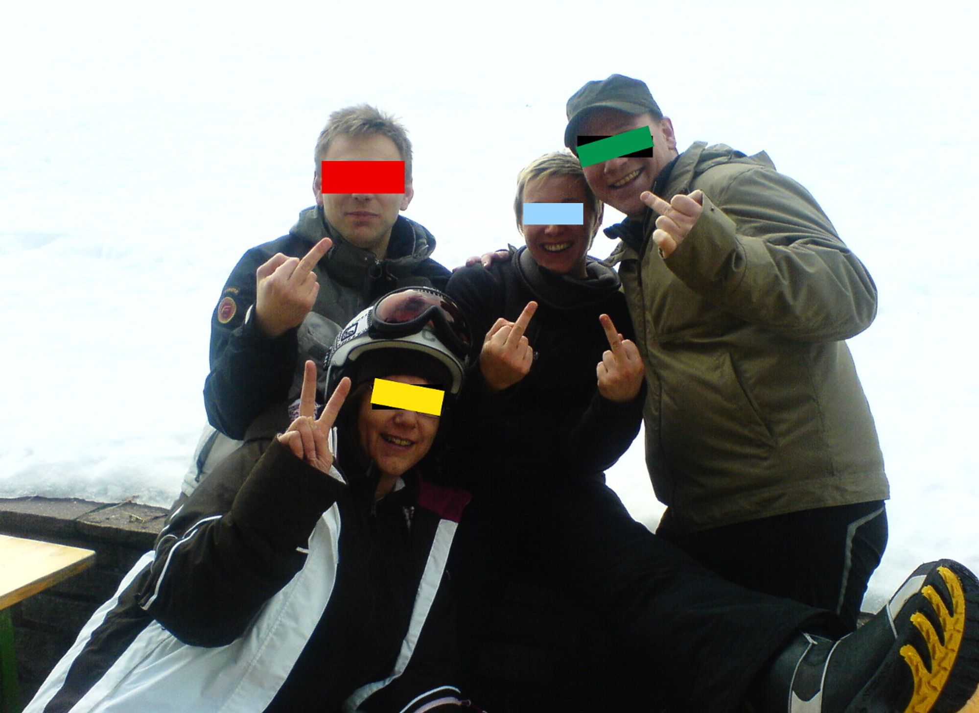 Farbfoto einer Gruppe von vier jüngeren Menschen bei einem Skiausflug in den Alpen, die posieren und dabei bekannte Fingerzeichen machen. Zum Schutz der Privatsphäre mit bunten Balken vor den Augen.