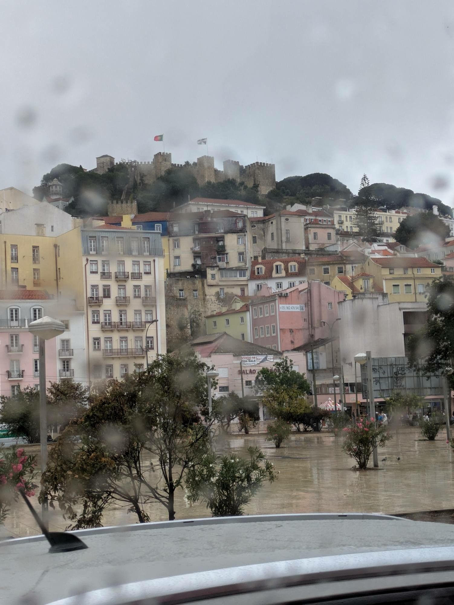 grauer Himmel 
unscharfe Regentropfen an der Scheibe und dahinter die Altstadt und Burg von Lissabon 