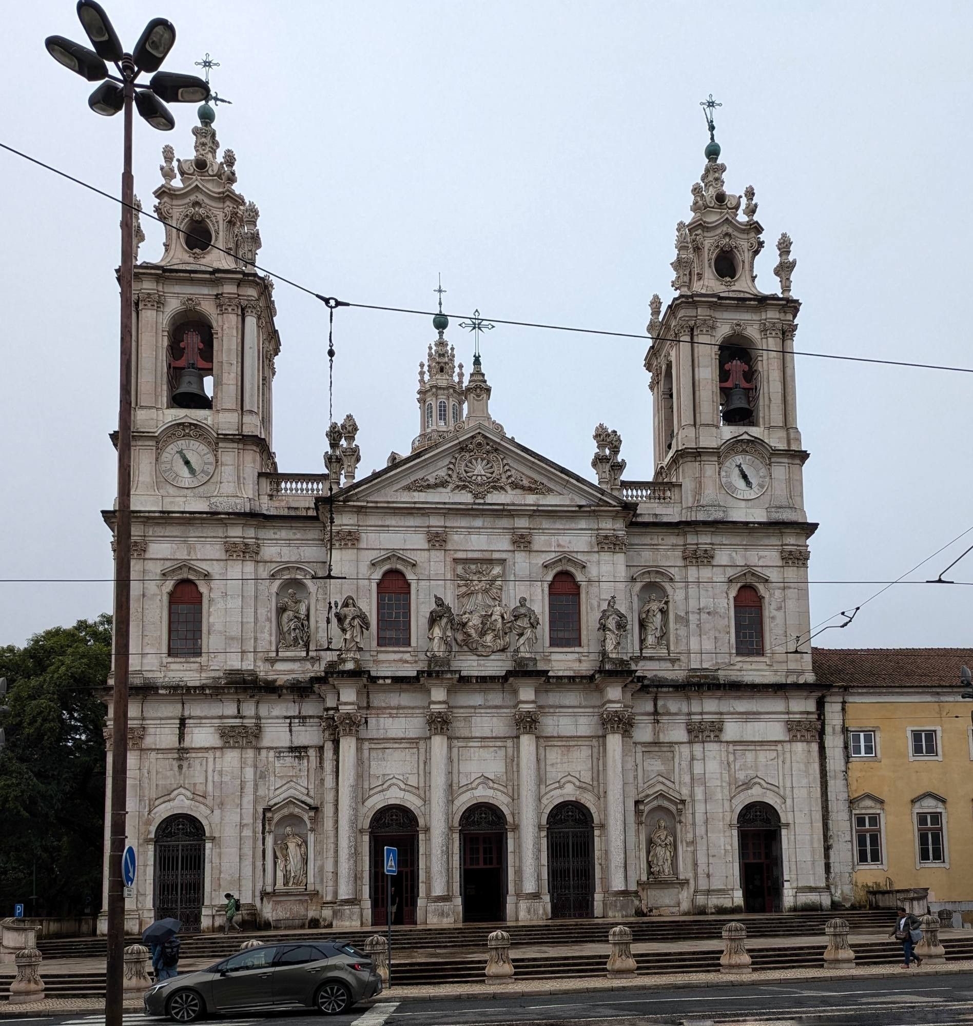 Vorderansicht einer großen Kirche mit zwei Türmen links und rechts. Sehr heller Stein. grauer Himmel