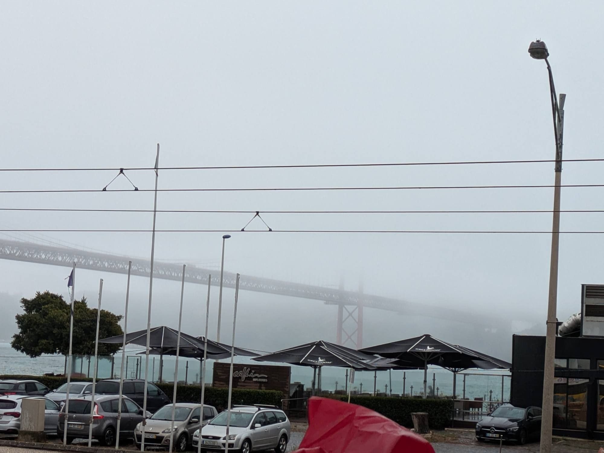 tiefhängende Wolken oder Nebel lässt von der großen Brücke über den Tejo nur einen Teil der Fahrbahn erahnen. Die Pfeiler verschwinden knapp drüber im gleichmäßigen Hellgrau