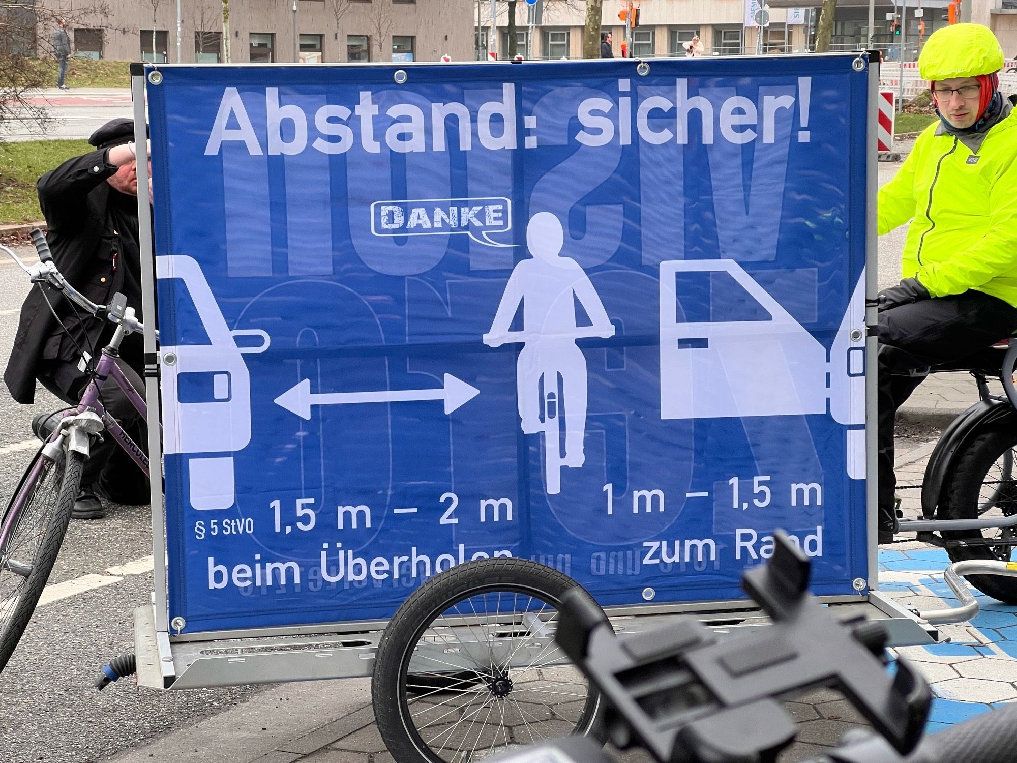 Schild auf Fahrradhänger: Abstand sicher!
Darunter Piktogramme, die den verpflichtenden Überholabstand f einspurige Fahrzeuge erklären.