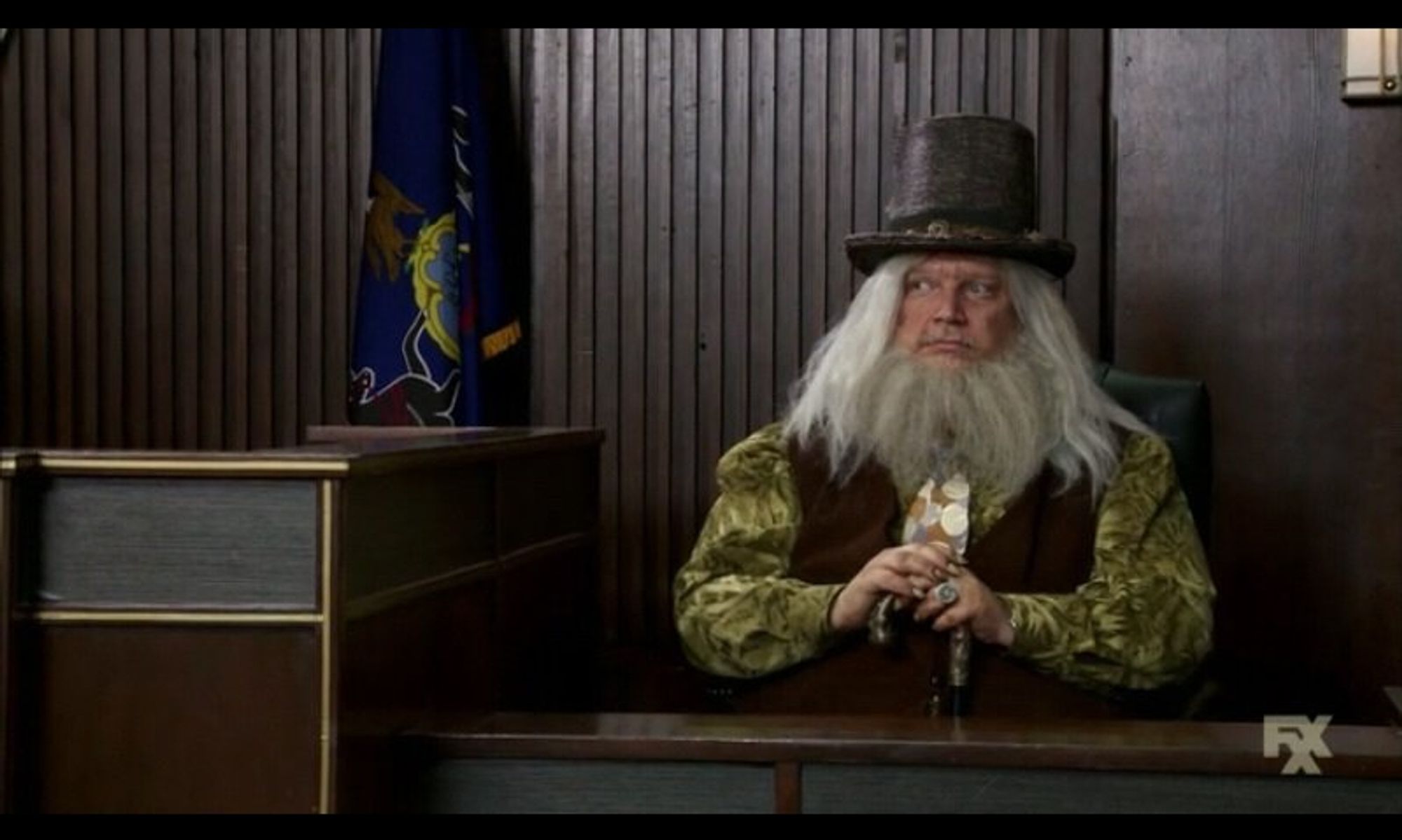 Pappy McPoyle on the witness stand. He wears a hat that hides a secret: Royal McPoyle, the deadliest bird in Philly.