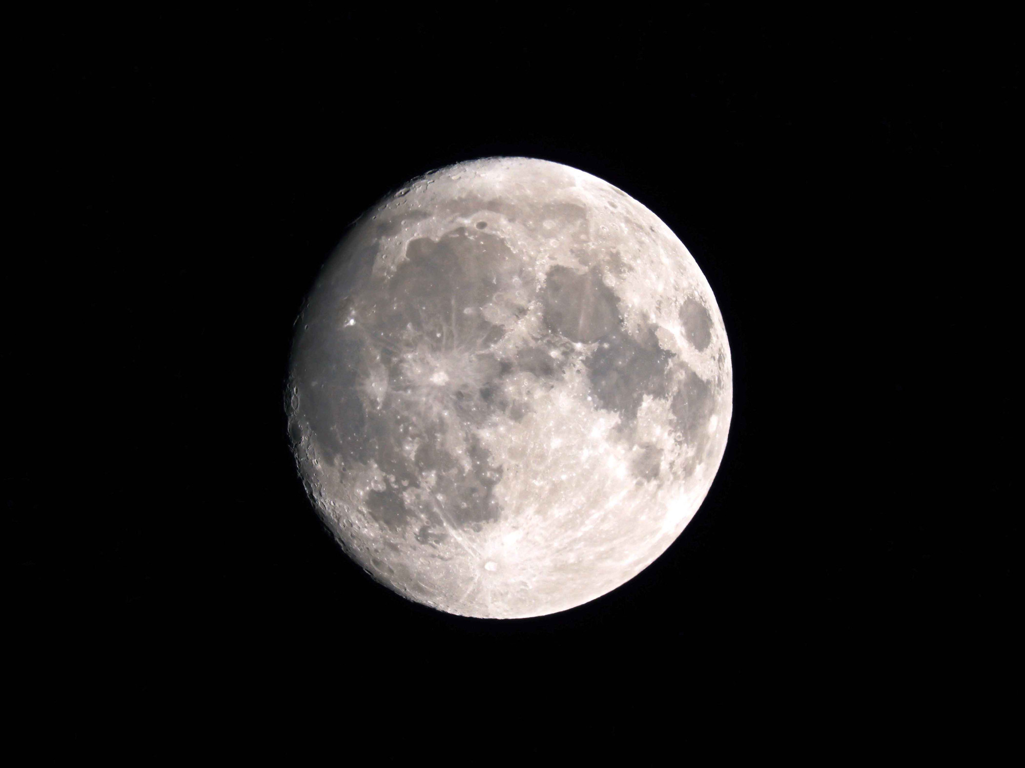 A hazy, almost full, waxing gibbous moon.