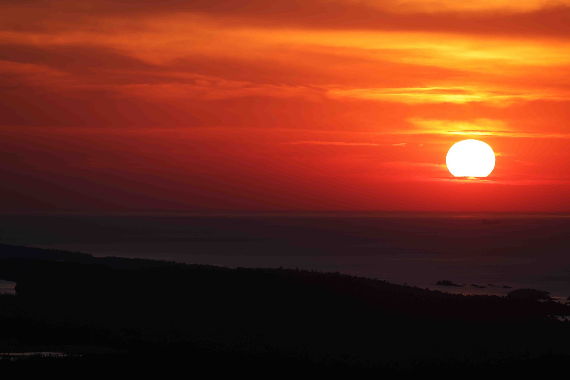 The Sun is a bright white ball surrounded by red/orange clouds as it dips into the waiting arms of Lake Superior. The coast of the UP is dark. It feels like a Rothko painting.