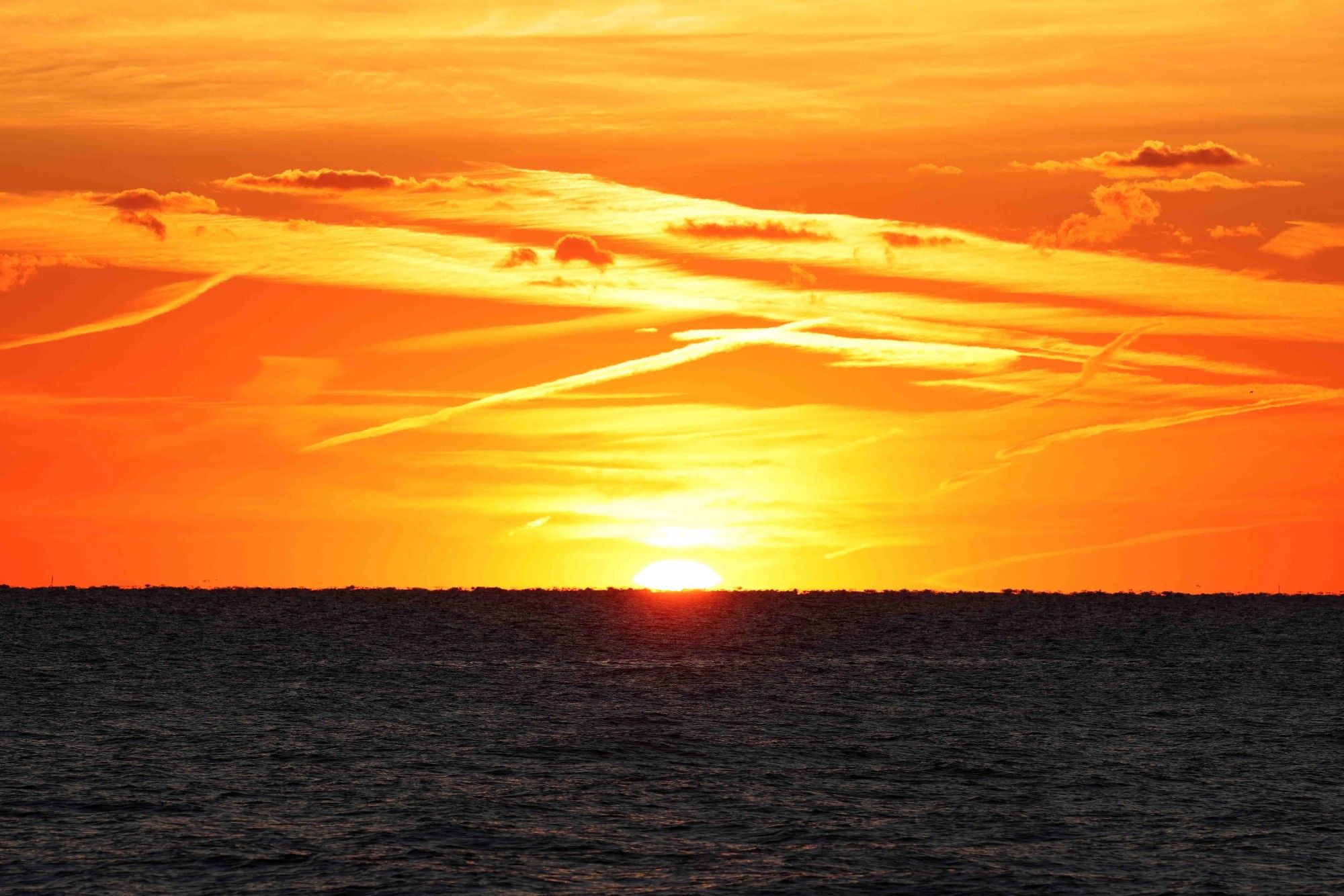 Sun is rising from Lake Michigan. Orange and yellow skies.