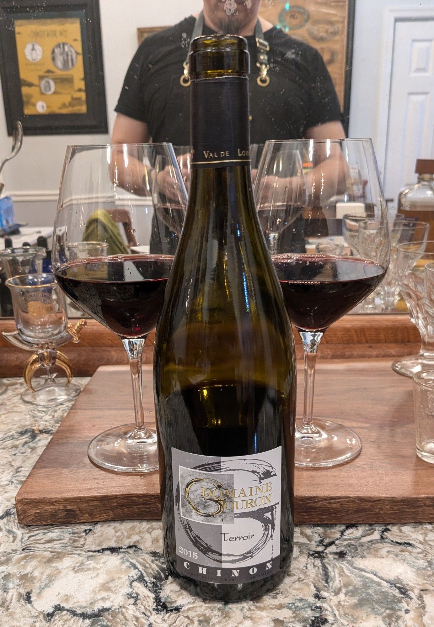 A bottle of Domaine Gouron wine from Chinon, with two glasses poured behind it.