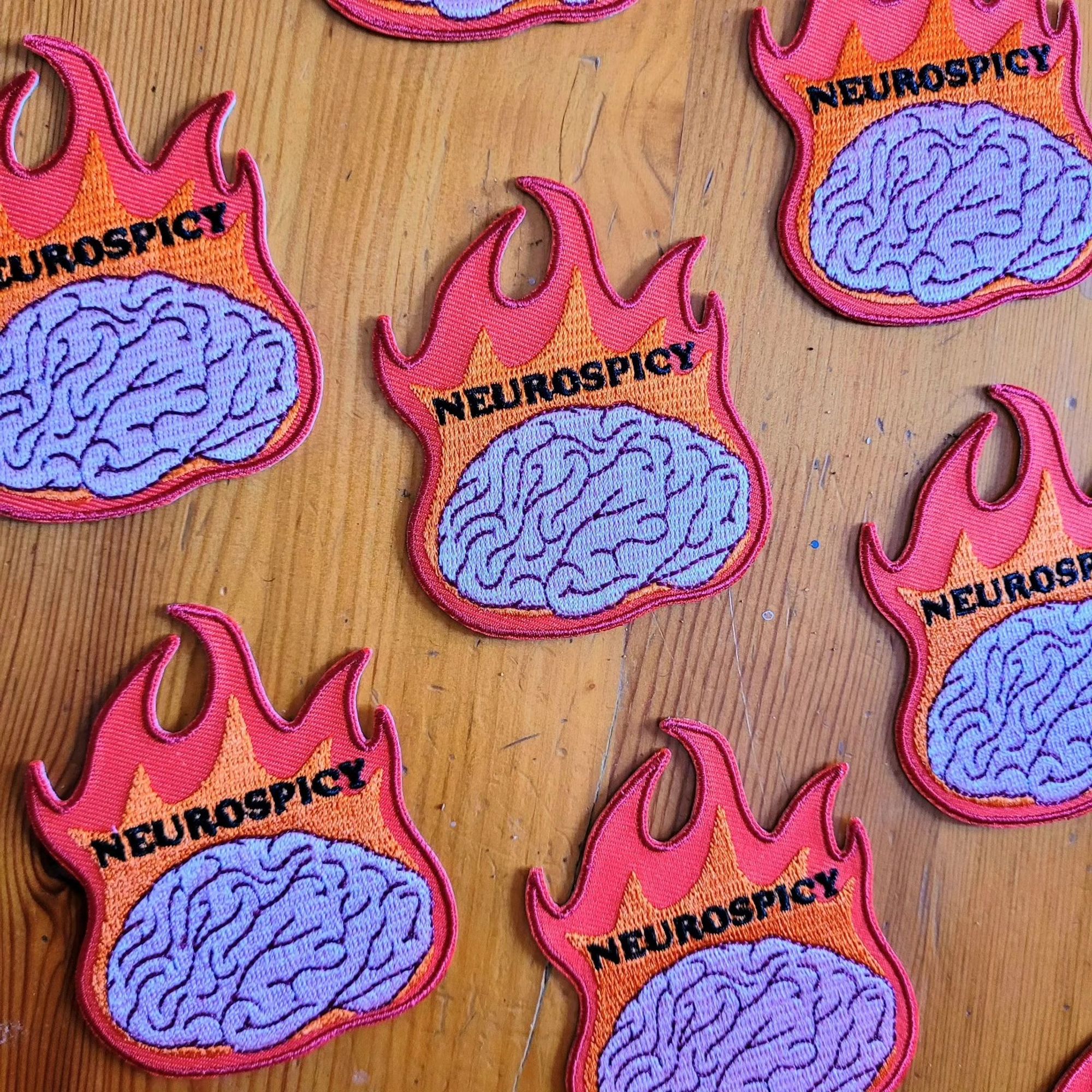 Iron-on patch of a brain on fire with the text Neurospicy.