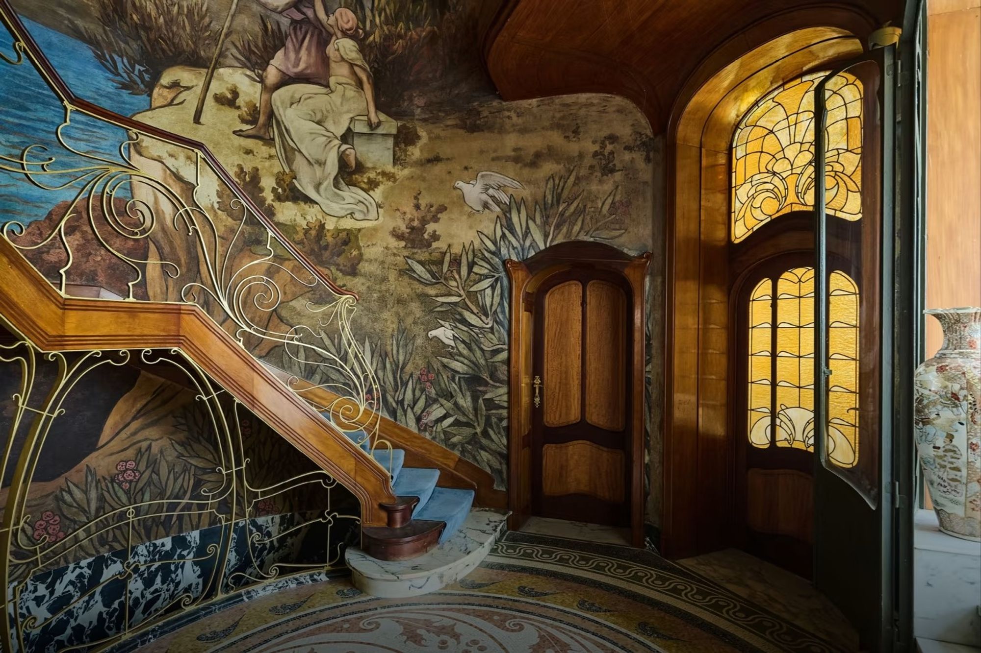 An Art Nouveau staircase decorated with curved patterns and soft colors, with a nature-themed background and rounded windows on the walls.