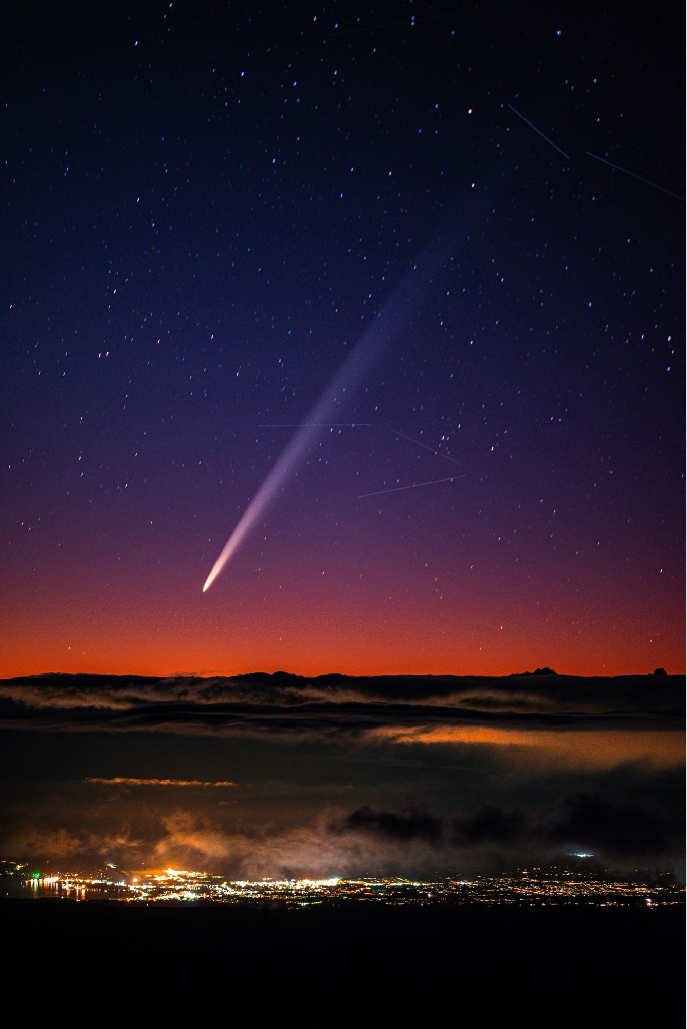 A meteor (or maybe shooting star) coming down across a purple and orange Big Island of Hawaii skyline.