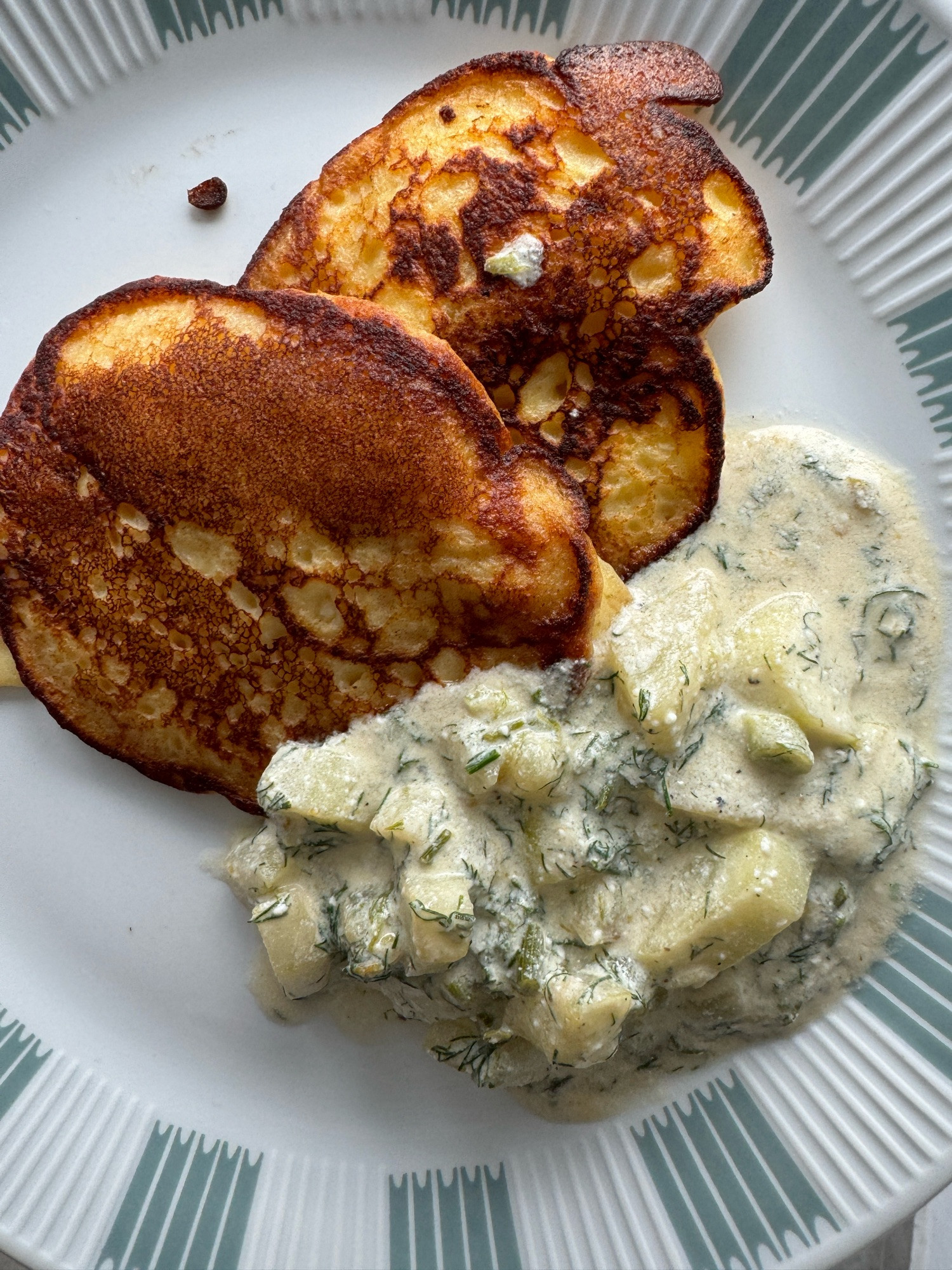 teller mit zwei blini und dem beschriebeneb gurkengemüse