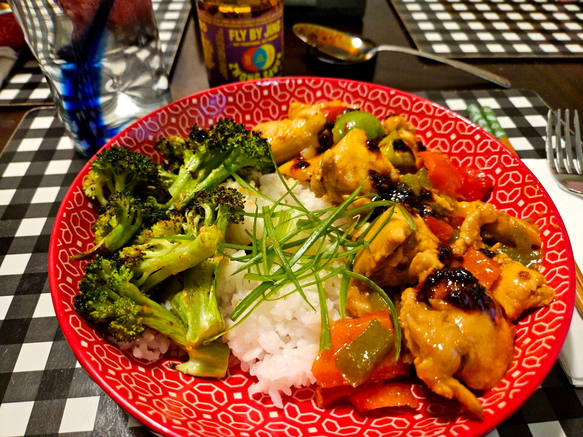 A rice bowl of Kung Pao chicken with a side of roasted broccoli.