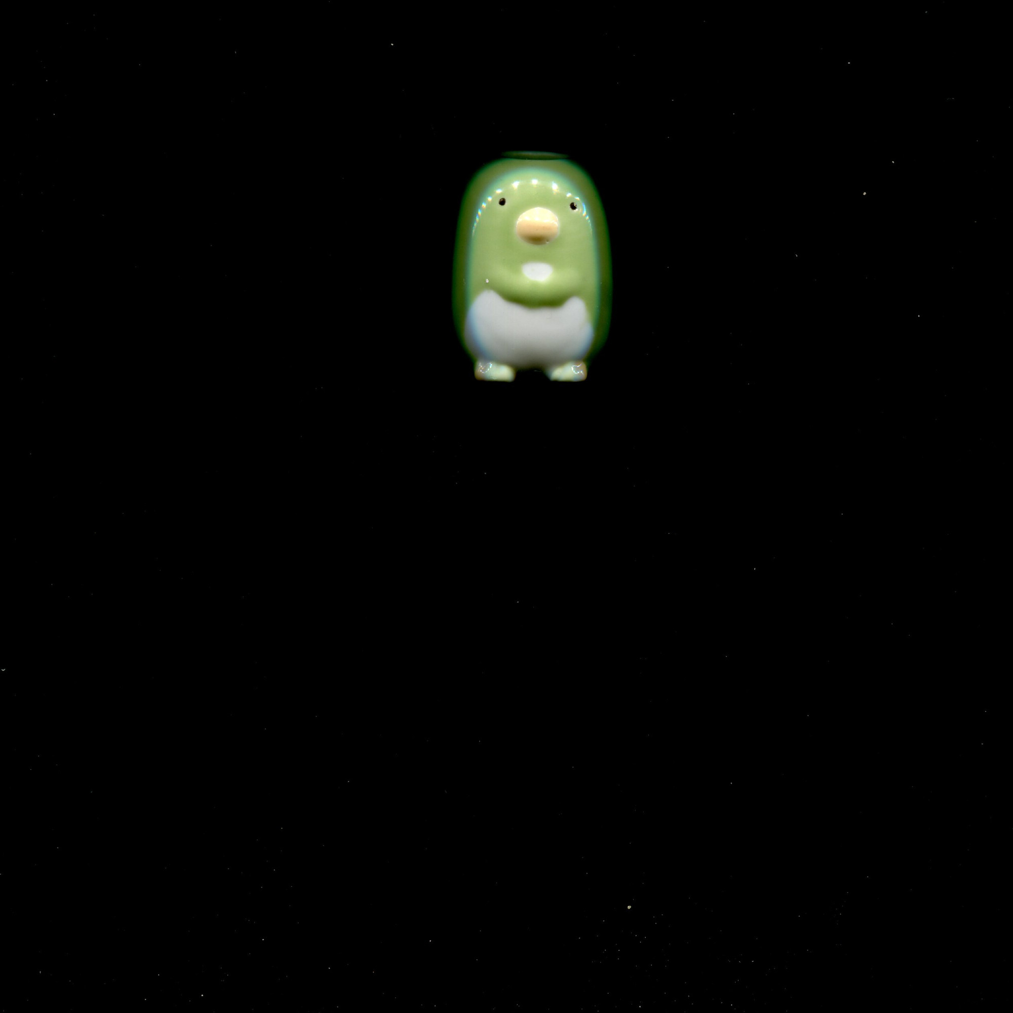 a green ceramic penguin pen holder hovers menacingly in the night sky