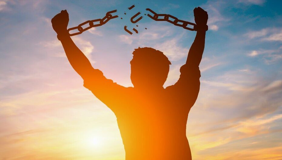 A man with his hands in the air breaking chains that linked them together.