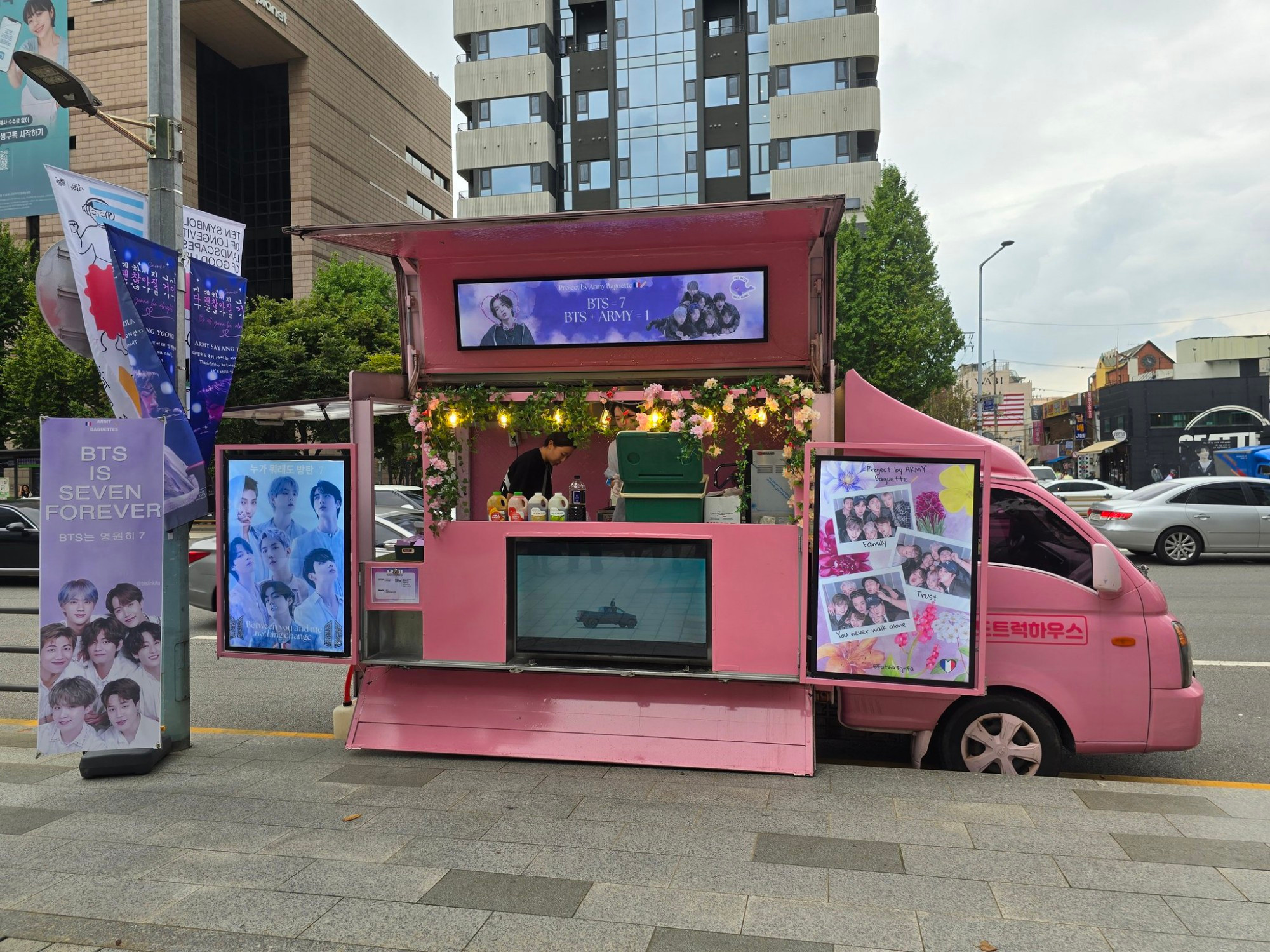 A food truck located in front of the street, color pink, with a large TV screen on front playing some BTS 's music vidéo. The song is Yet to come
There are some banners where IS written ''BTS is Seven forever''.
On top on the food truck there is a large photo  : at left Yoongi in a heart frame , center  the words  BTS = 7 BtS + ARMY =1, at right  all the members together reunited