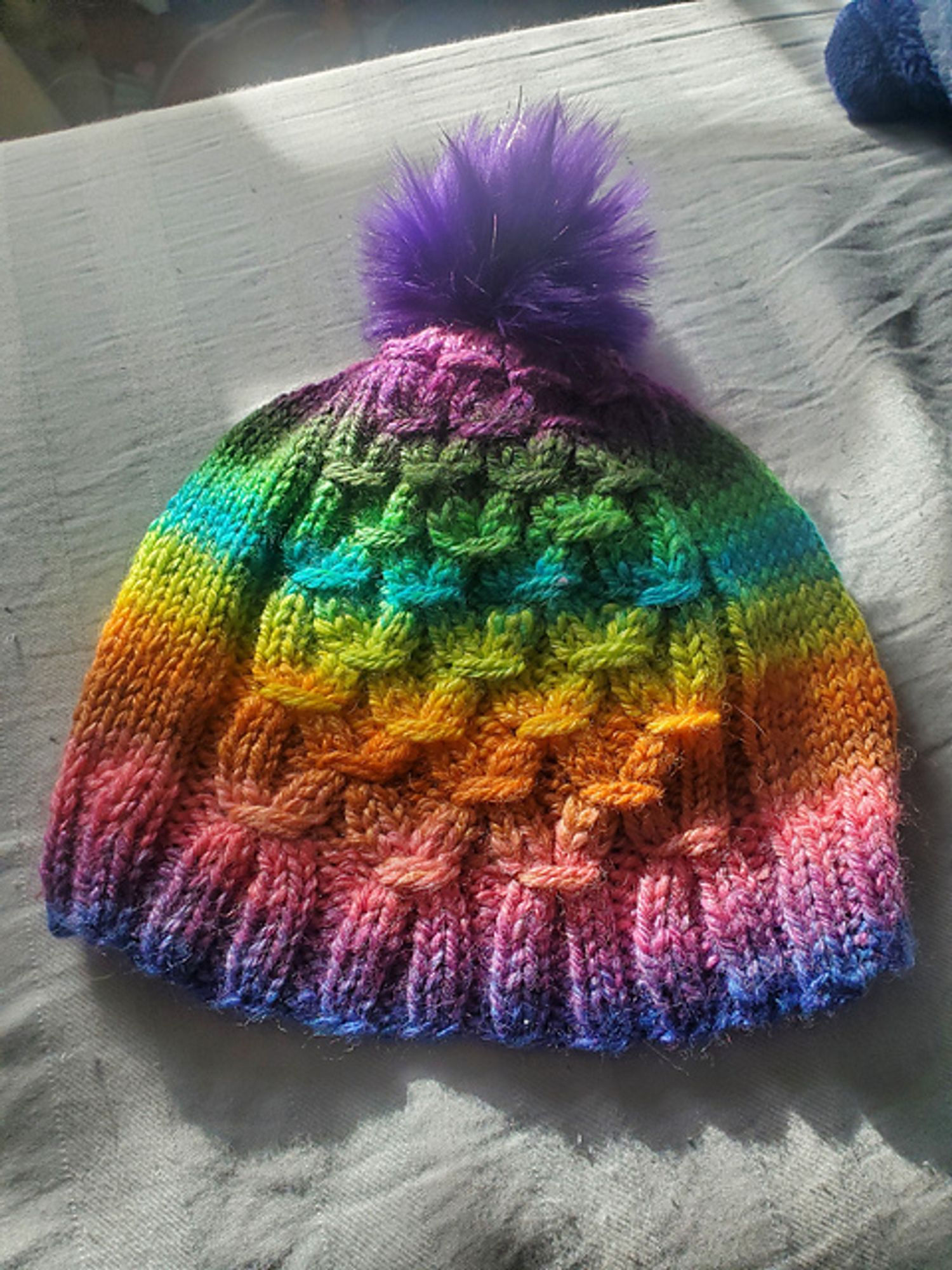 A hat knit from handspun for my kiddo from Tin Can Knits' Gather pattern. The colors are nearly a full rainbow, and it's topped with a purple sparkly pompom.