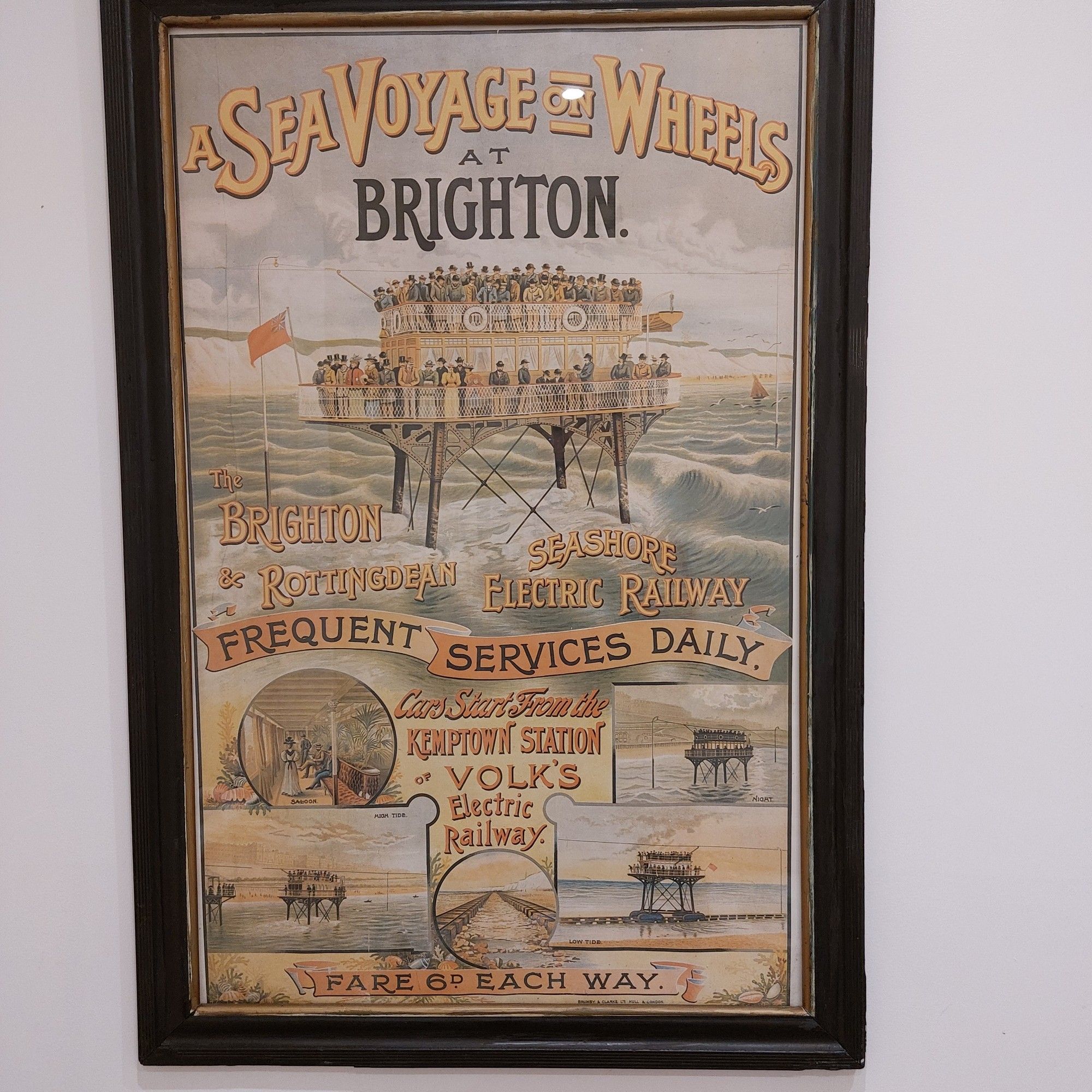 Framed reproduction of an Edwardian poster seen in a cafe bathroom, advertising a shallow water electric railway at Brighton on the south coast of England.