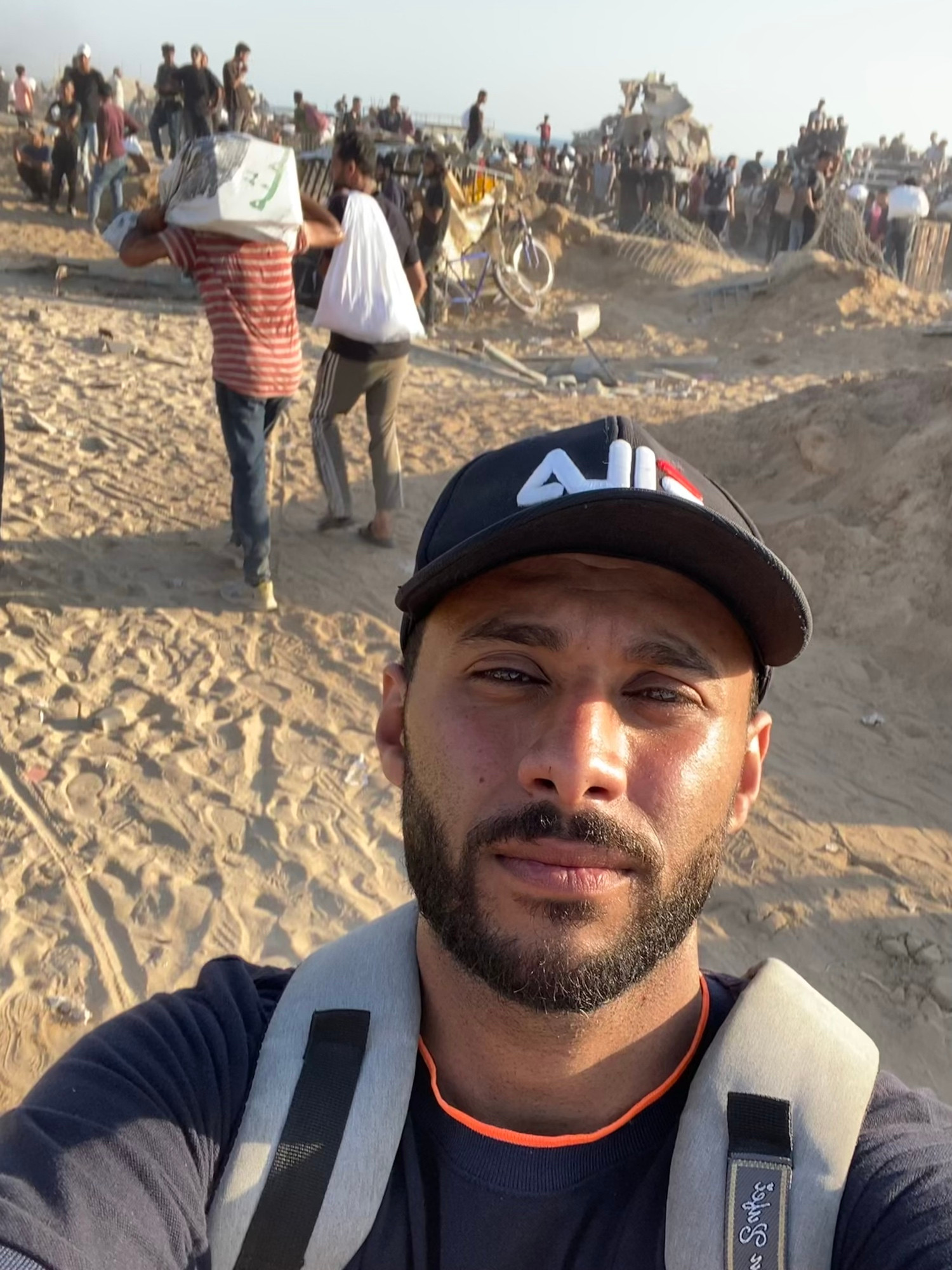 A young man from Gaza sits with a solemn face, holding on to hope in the middle of destruction. His eyes carry the weight of war, hunger, and loss — yet he still believes in the kindness of strangers. This image is a silent plea for help, dignity, and survival.