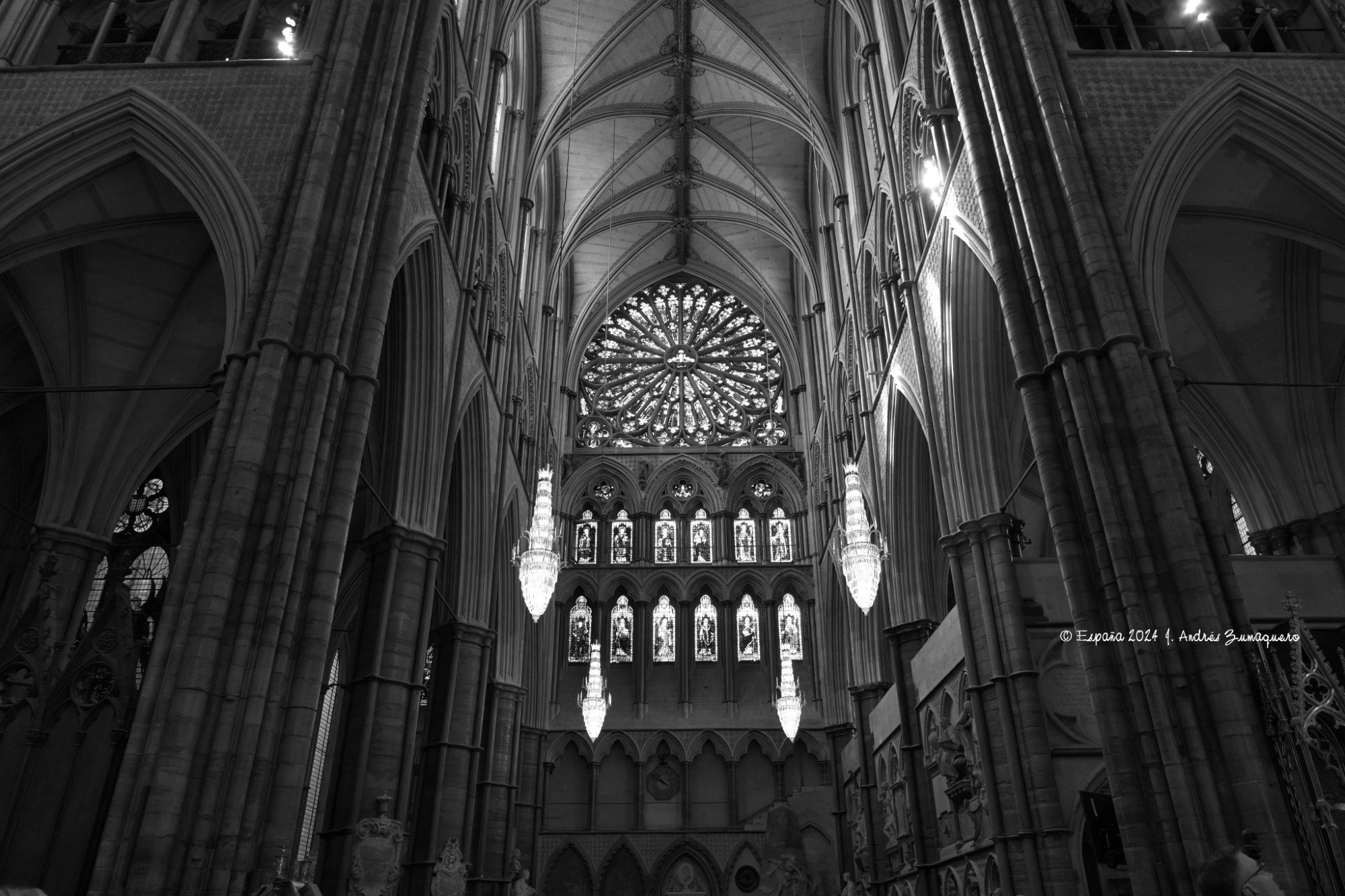 Imagen en blanco y negro del interior de la Abadía de Westminster donde aparece el rosetón y otras vidrieras. Pueden verse algunos de los arcos de su arquitectura.