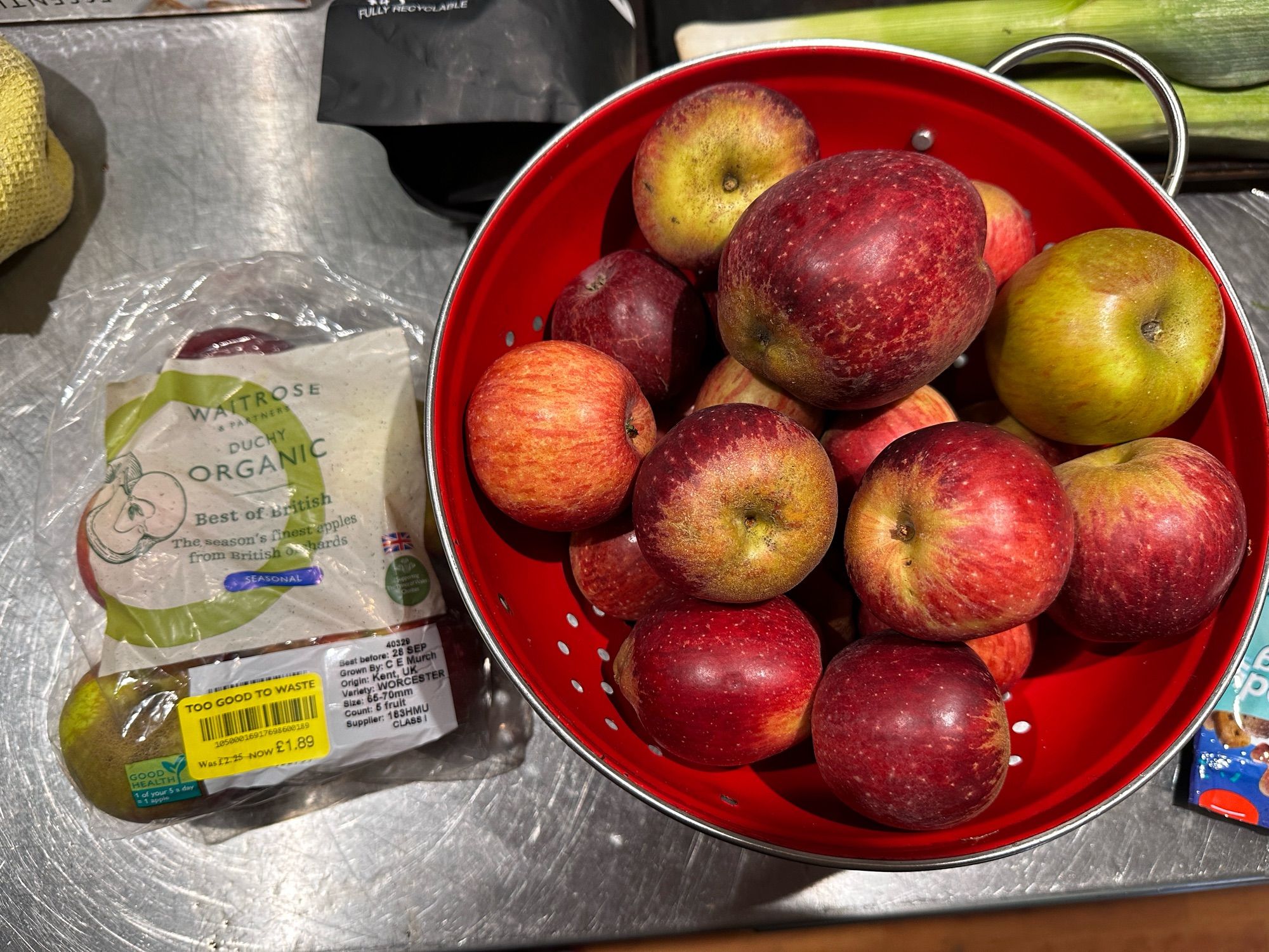 On my kitchen counter top a bag of Duchy Apples from Waitrose sits next to a red colander of mixed apples lifted from a local orchard.