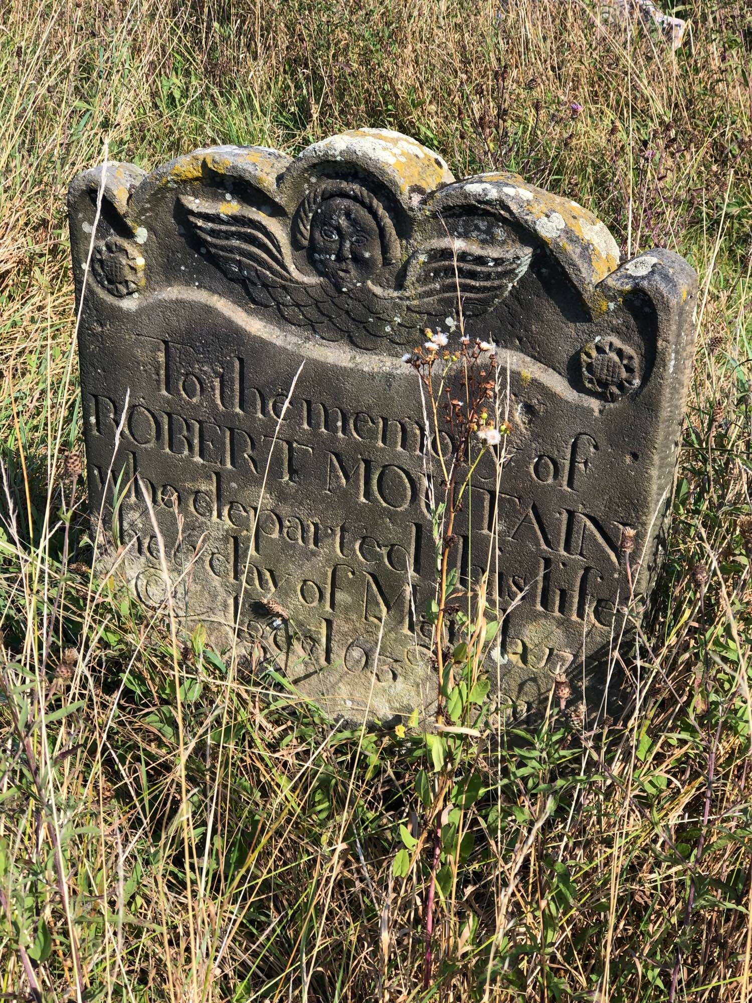 A gravestone with a wingéd head